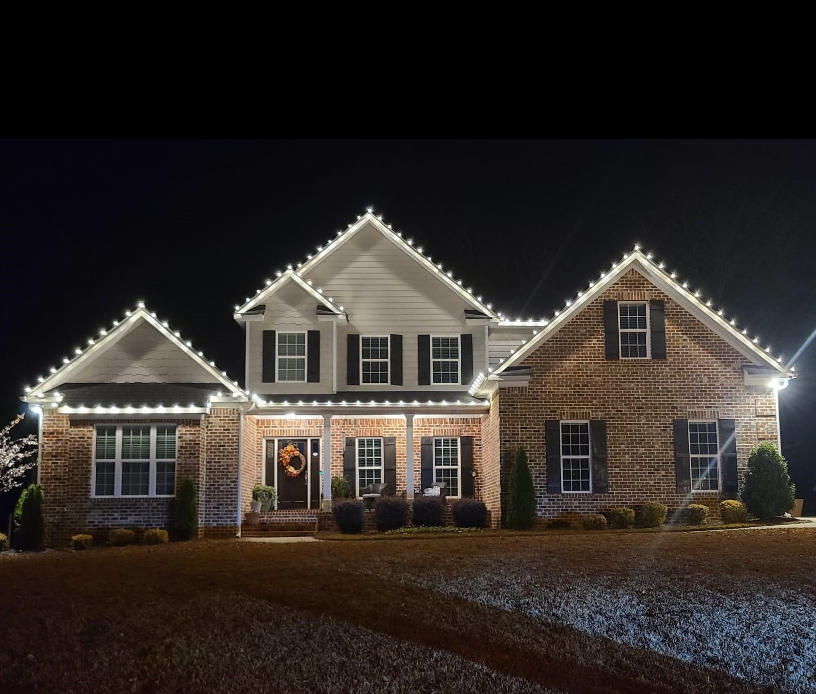 Bright warm white holiday roofline lighting reflecting over Lake Sinclair, GA.