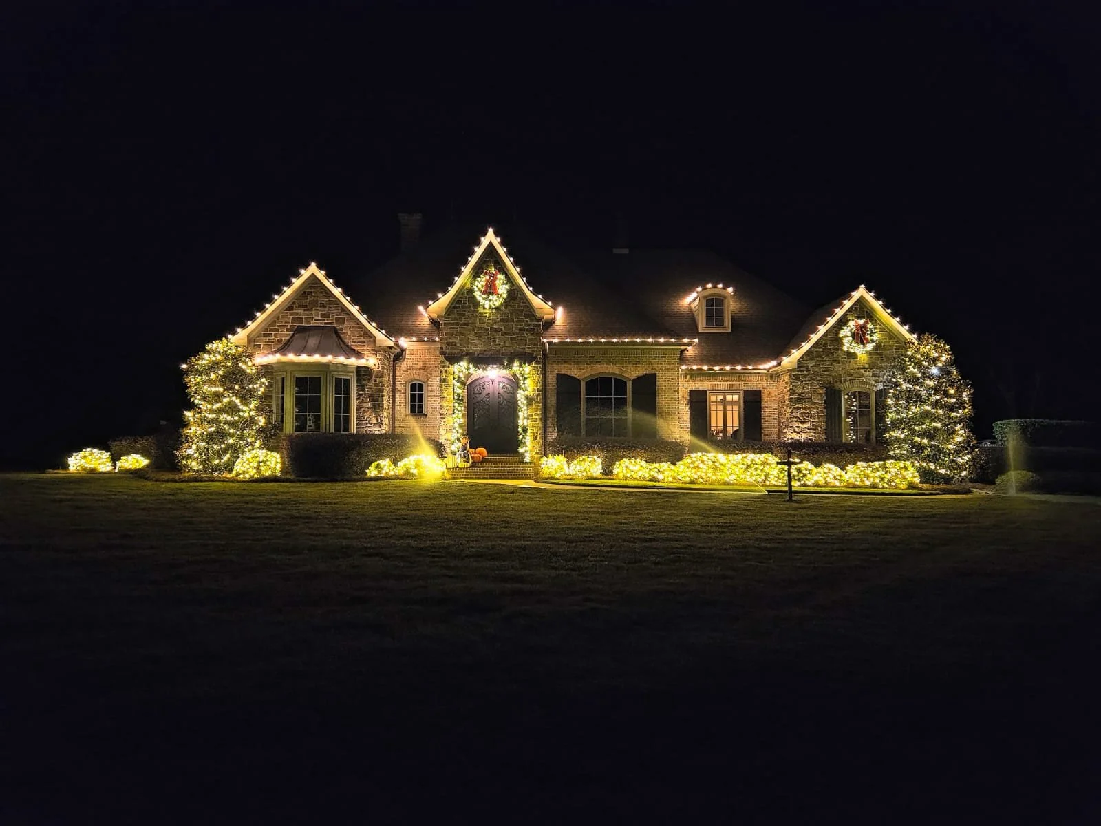 A house decorated with Christmas lights and wreaths at night.