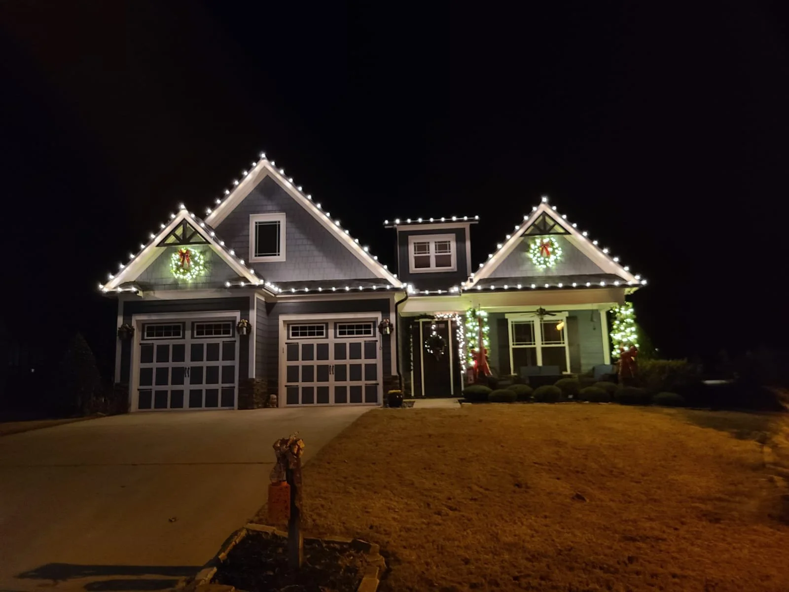 Pre-lit entry wreaths and lit greenery accents on a lakefront property in Lake Sinclair, Georgia.