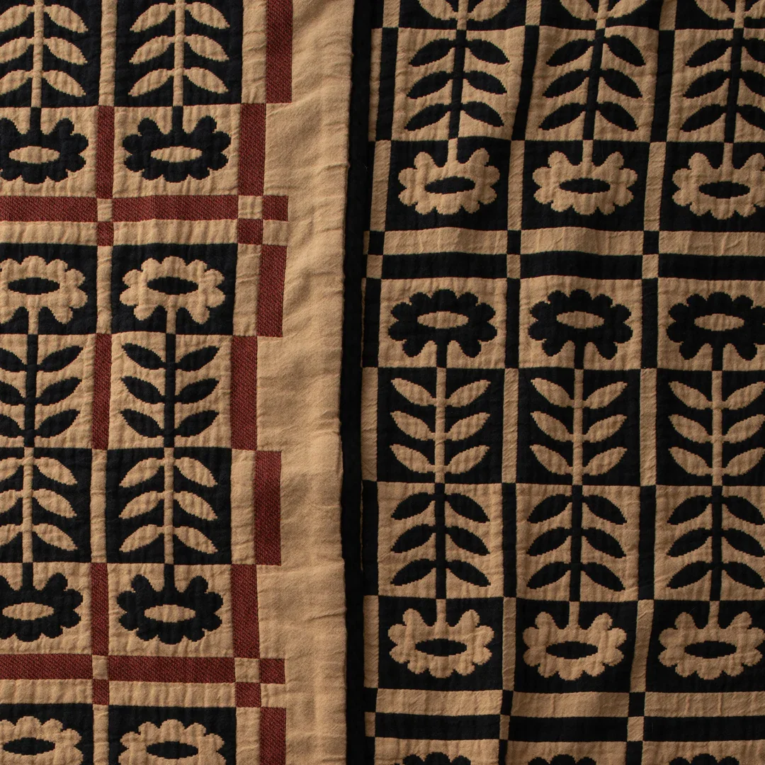 Close-up of a textile with a black and beige geometric floral pattern, featuring a red border on the left side.