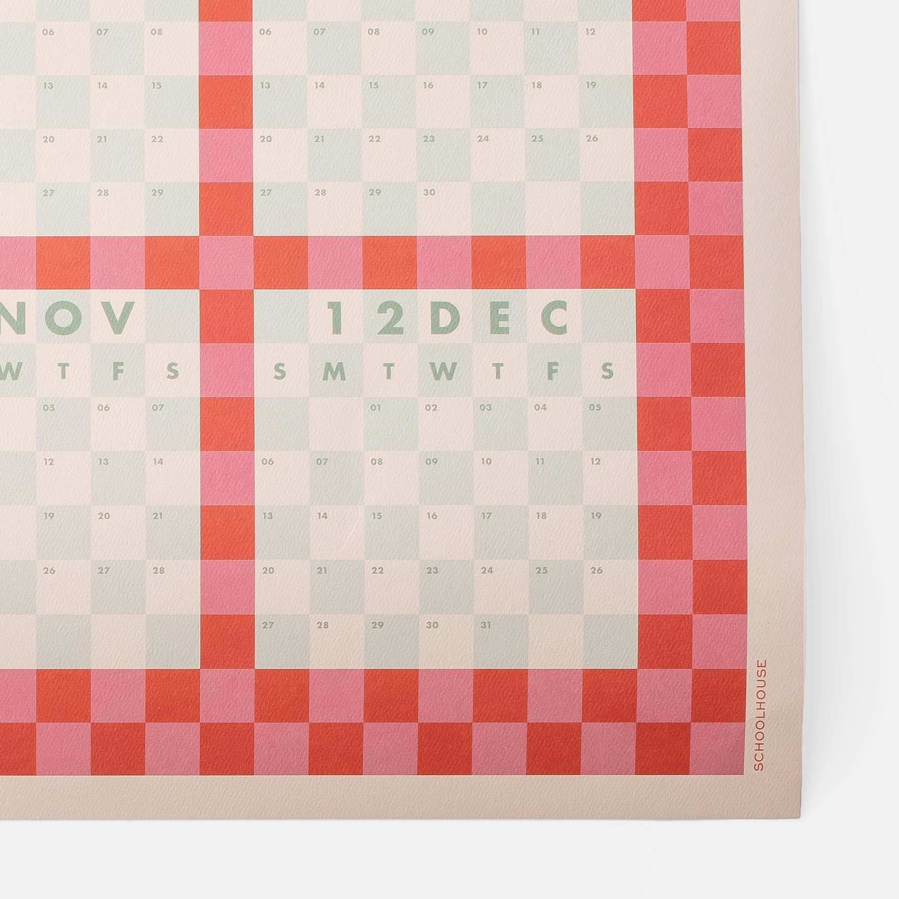 A colorful calendar with a grid pattern of blocks in shades of red, pink, and beige. The months November, December, and January are visible at the bottom, with the days of the week and numbered dates overlaid.