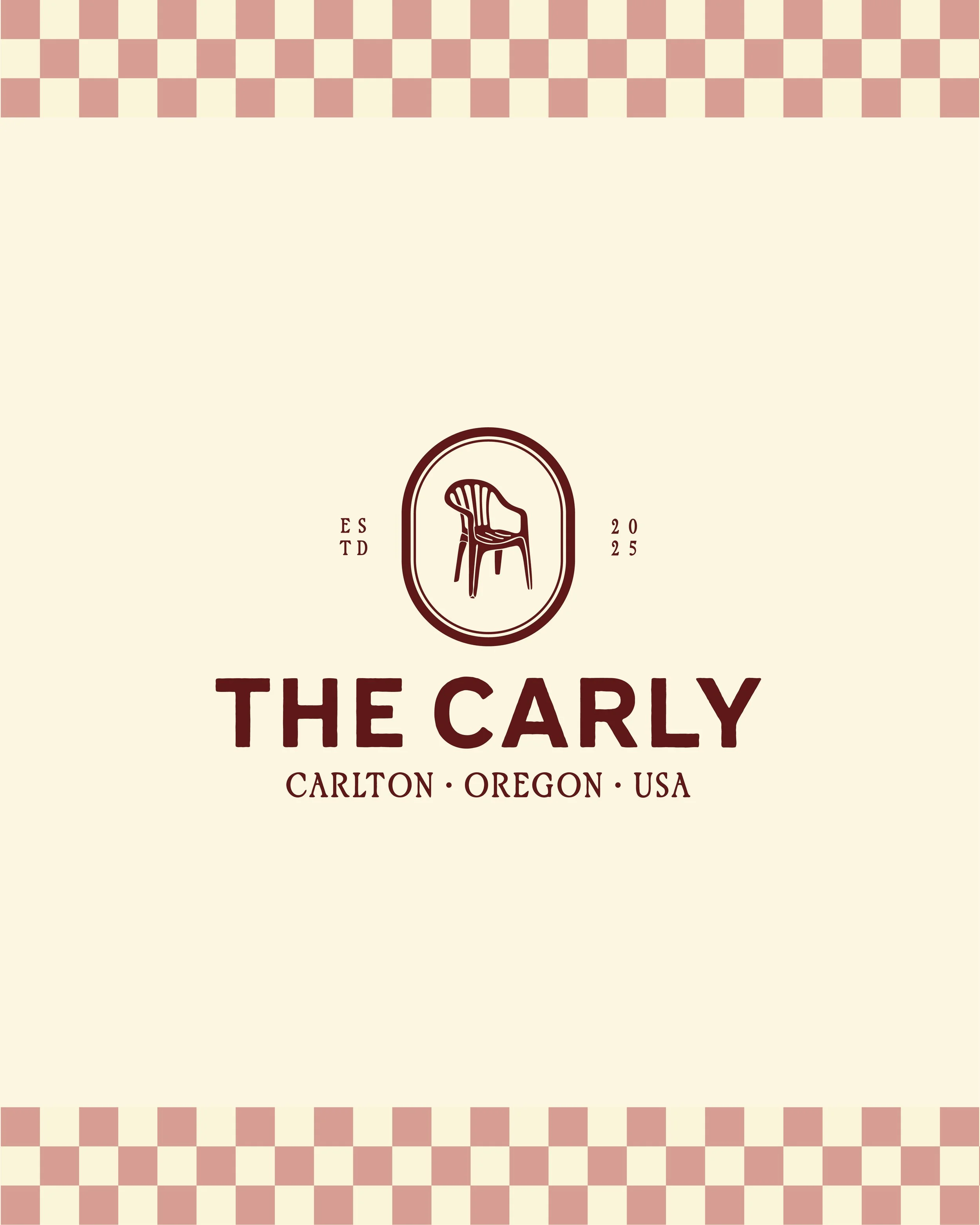 Close-up of a sign for The Carly restaurant in Carlton, Oregon, USA, featuring a chair logo and checkered border detail.