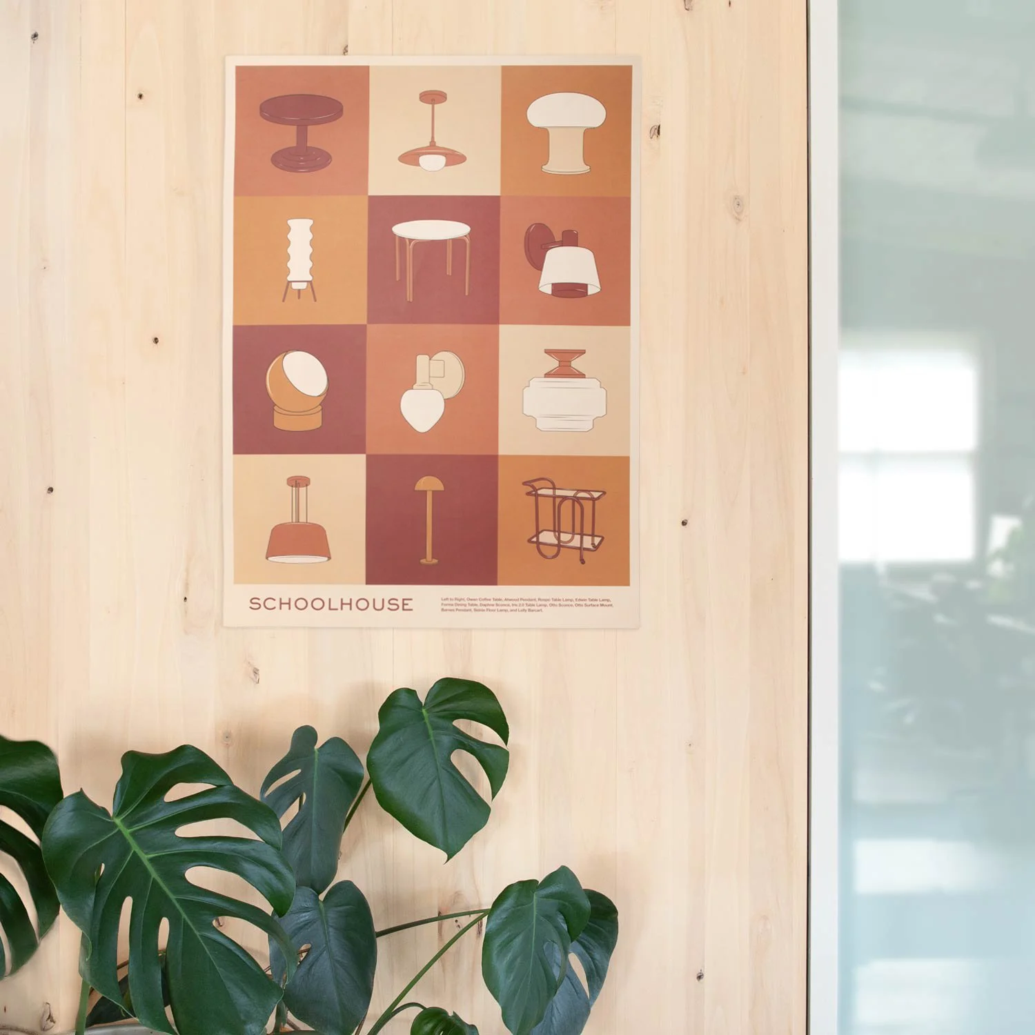 Poster displaying minimalist illustrations of various lamps and lighting fixtures arranged in a grid. The poster is titled 'SCHOOLHOUSE' and is mounted on a light wood-paneled wall, with green plants in the foreground.