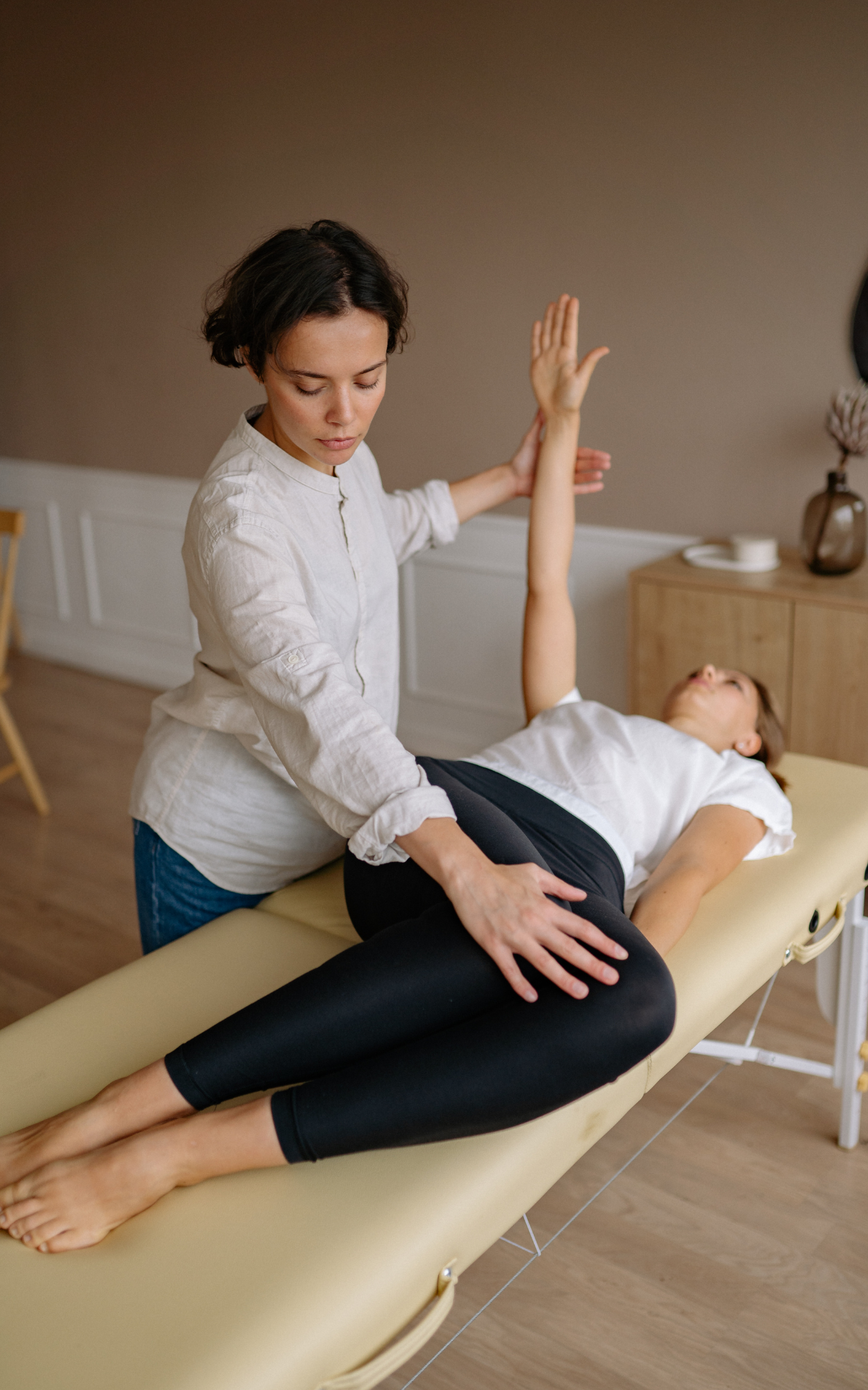 A woman receiving physical therapy or chiropractic adjustment from a healthcare professional in a clinical setting.