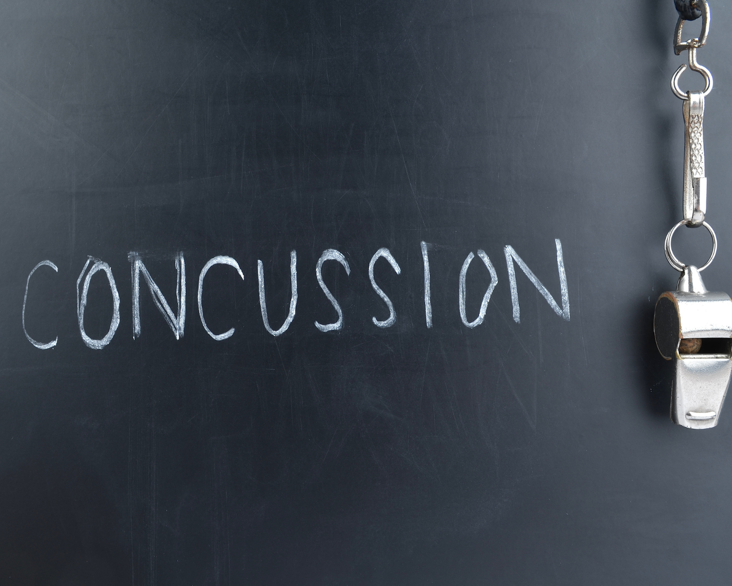 Chalkboard with the word 'CONCUSSION' written in white chalk and a metal whistle hanging on the right side.