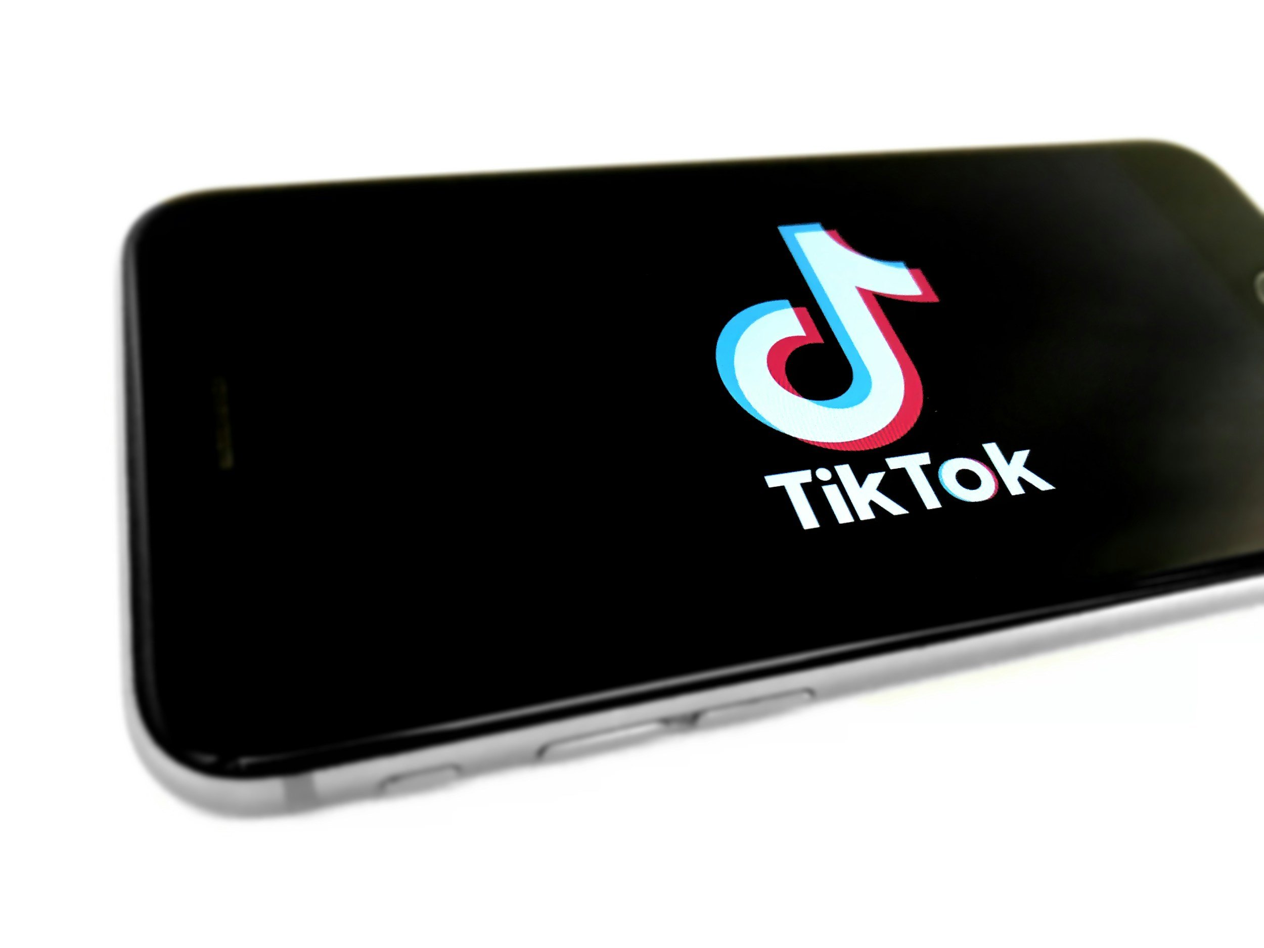 Close-up of a smartphone screen displaying the TikTok app logo, with the phone angled to the side.