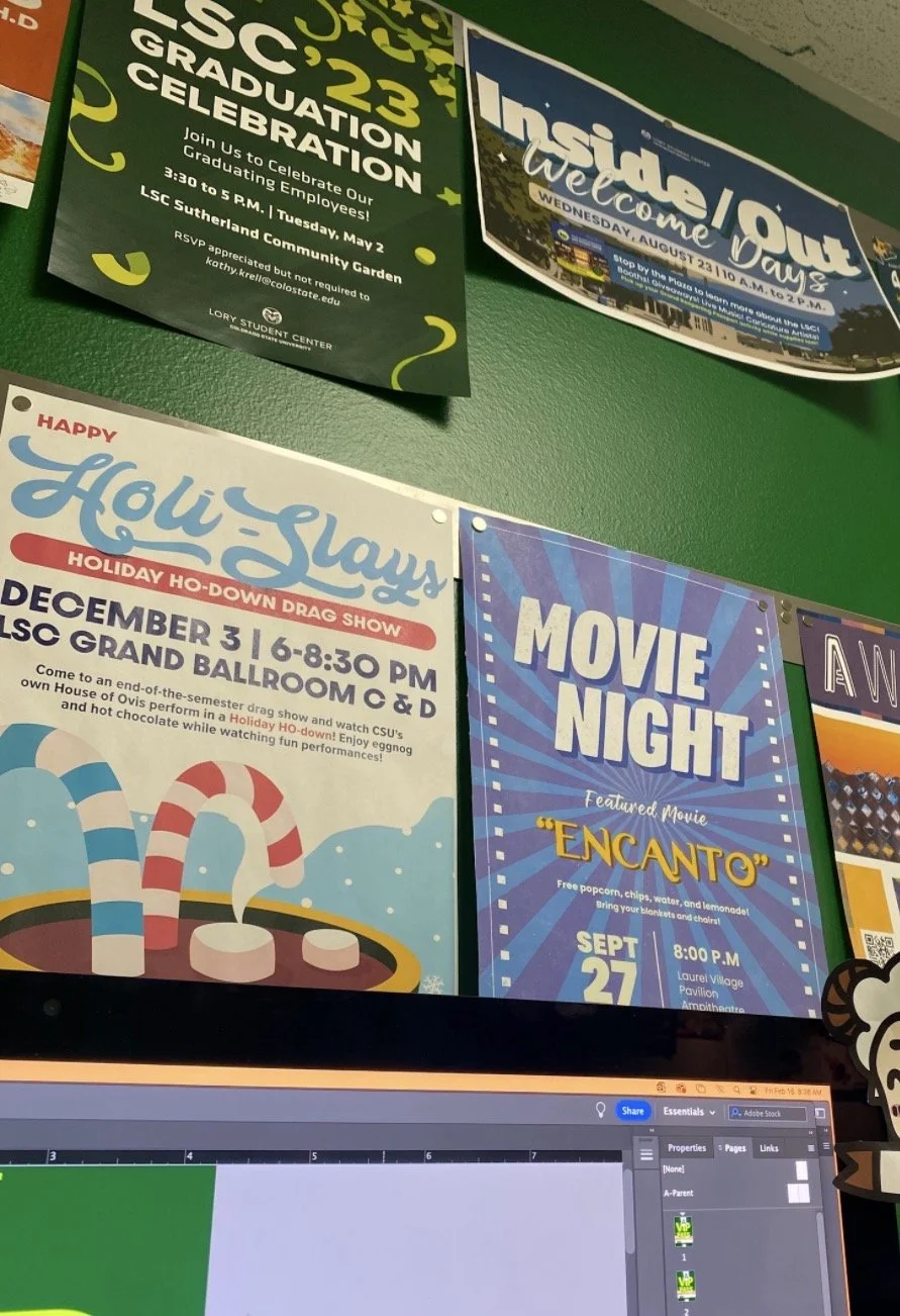 Posters on a green wall advertising various community events, including a graduation celebration, a holiday Ho-Down drag show, and a movie night featuring the film 'Encanto'.