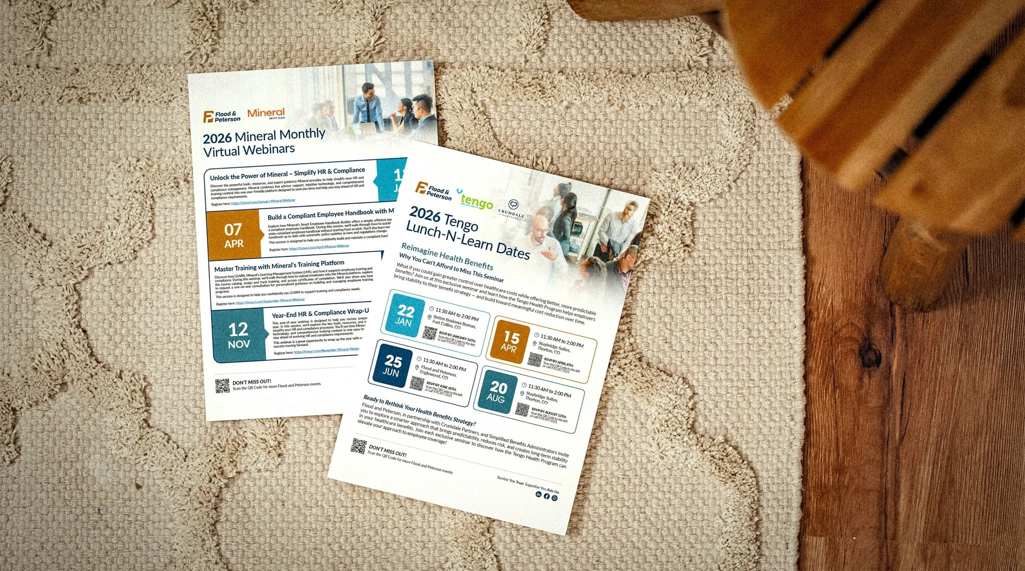 Two printed event flyers for virtual webinars placed on a beige carpet next to a wooden piece of furniture.