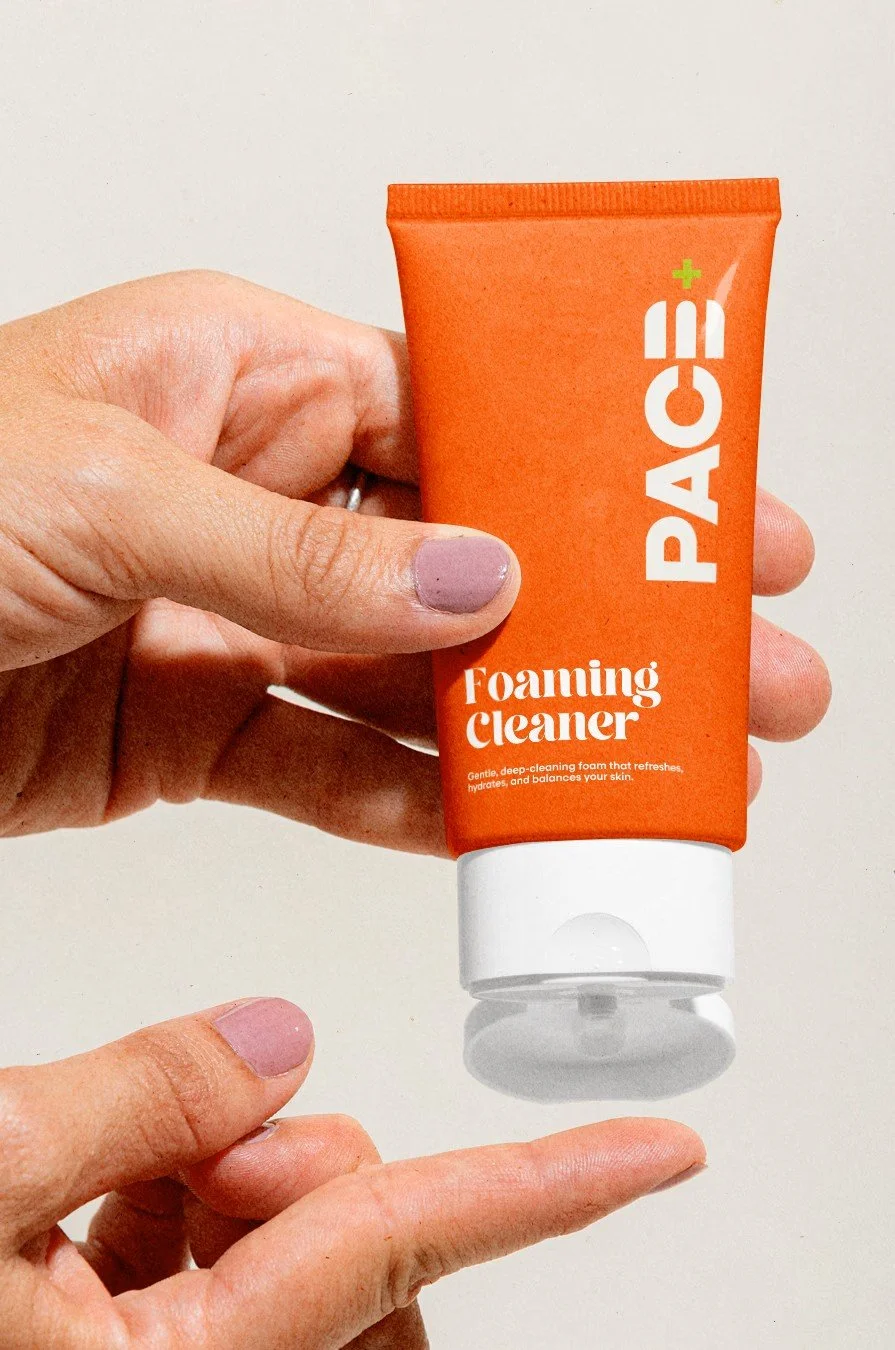 Hand holding a tube of Paige Foaming Cleanser, with the person applying it to their finger.