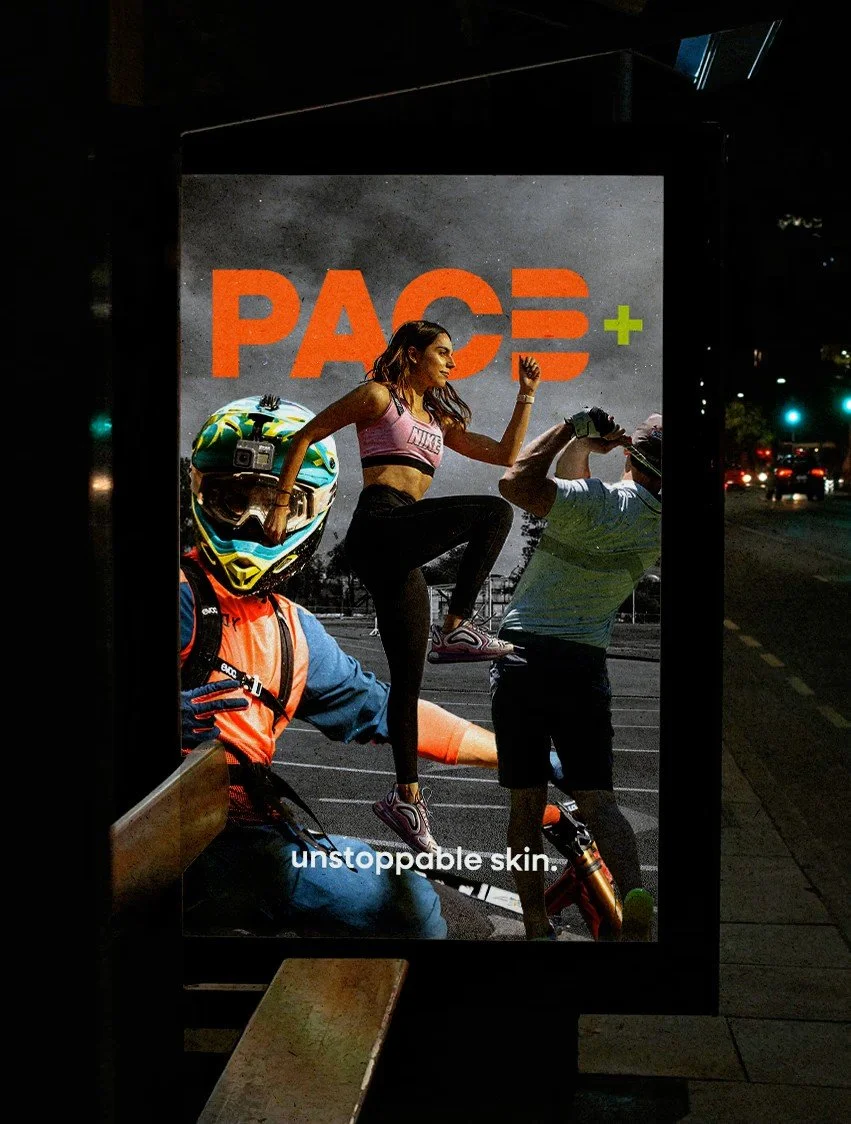A lit outdoor advertisement at night featuring a woman in workout clothes performing a high knee raise with a man in workout gear and helmet close by, against a backdrop with the text "PACE+" and the caption "unstoppable skin."