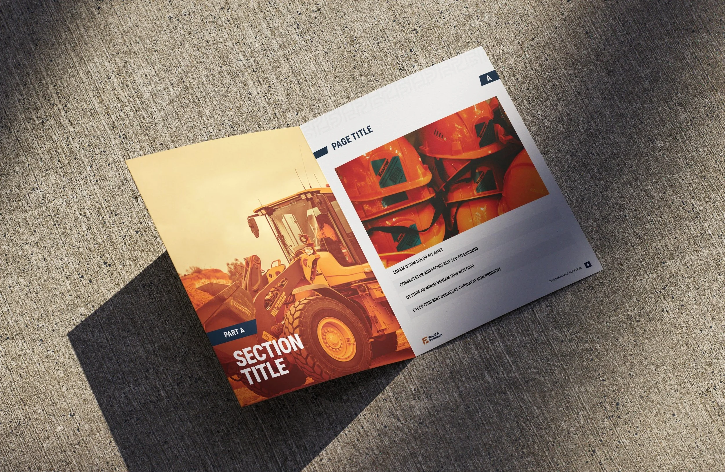 Open construction equipment catalog showing orange construction helmets and a yellow excavator on a textured surface.