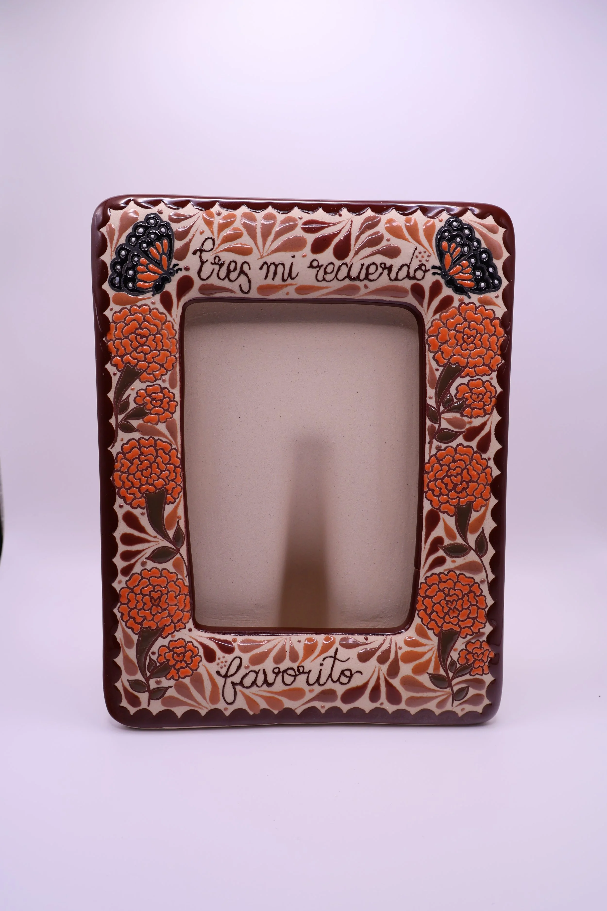 Decorative picture frame with orange floral and black butterfly designs, with the words "Eres mi recuerdo" at the top and "Favorito" at the bottom.