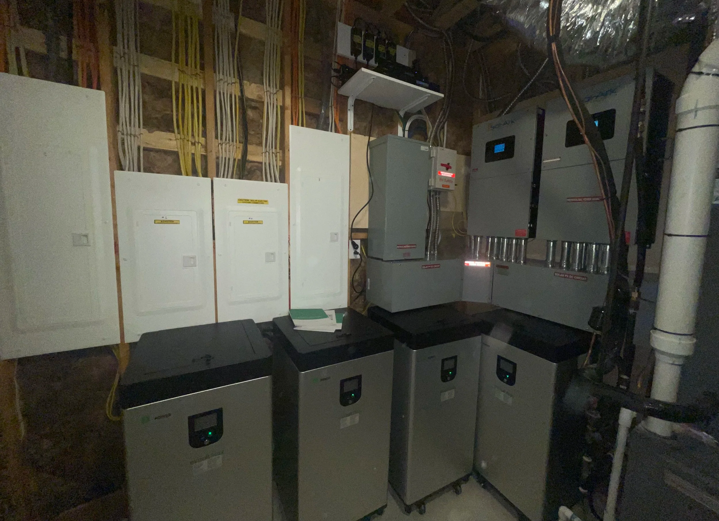A utility room with 80 KWh of Batteries including circuit breaker panels, power inverters, and wiring.