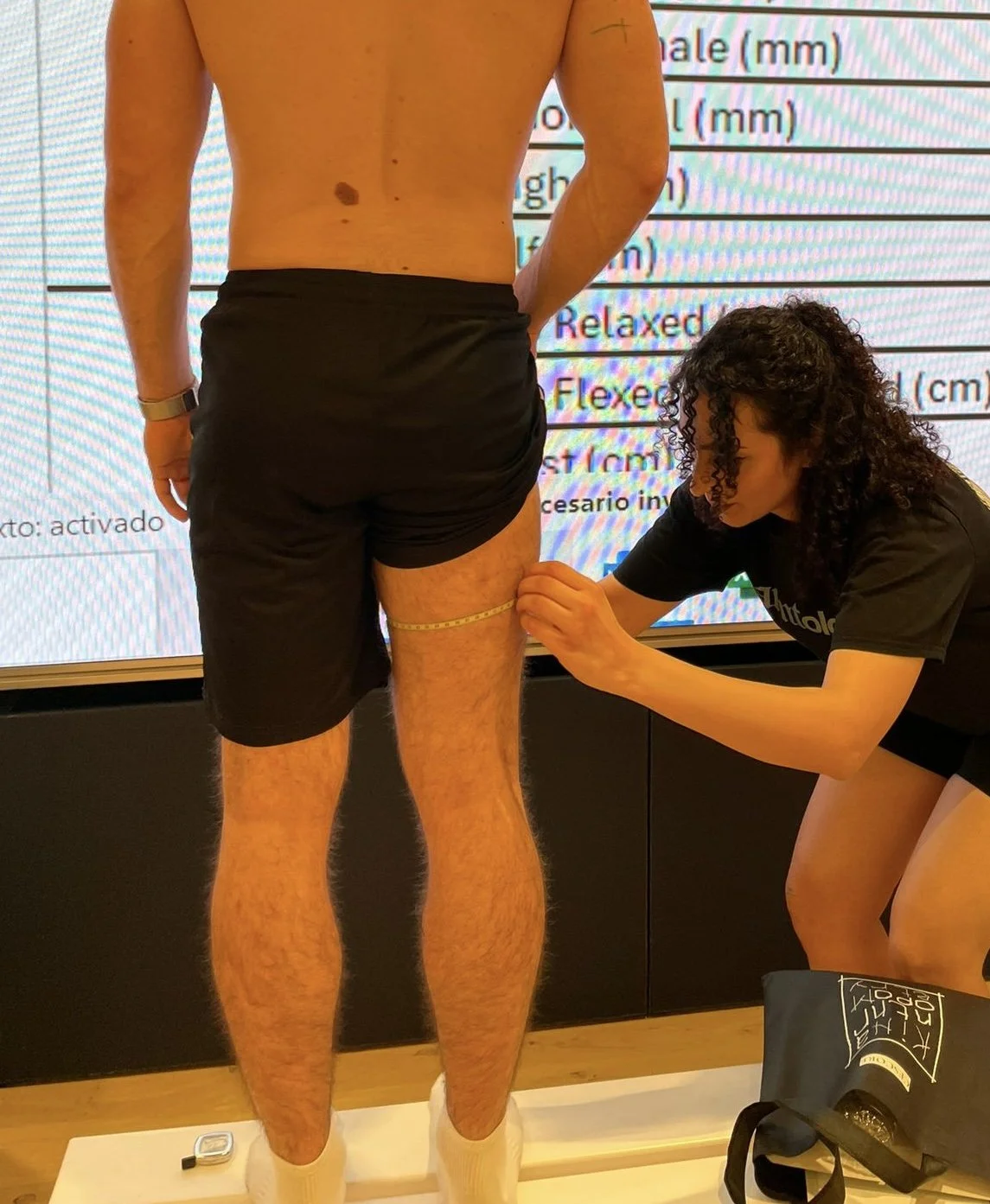 Une femme prend la mesure de la circonférence de la cuisse d'un homme lors d'une séance de mesure musculaire.