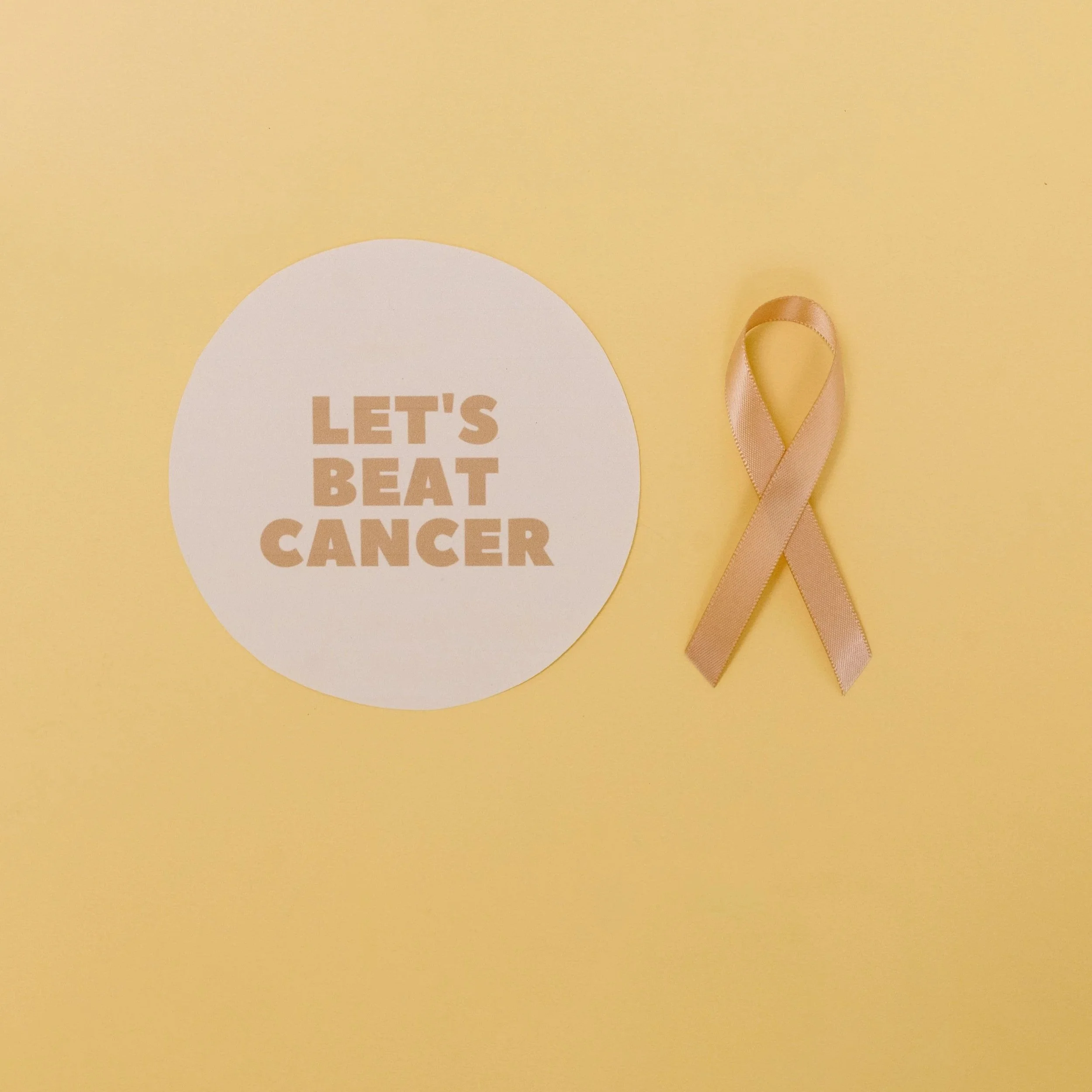 Une carte de sensibilisation au cancer du sein avec un ruban de sensibilisation rose à côté, sur un fond jaune