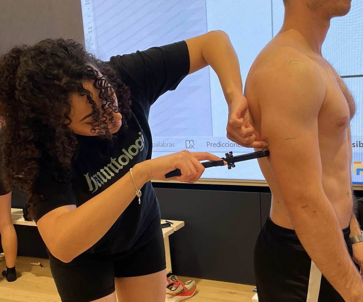 Une femme en train de prendre les mesures du torse d'un homme nu avec un outil de mesure.