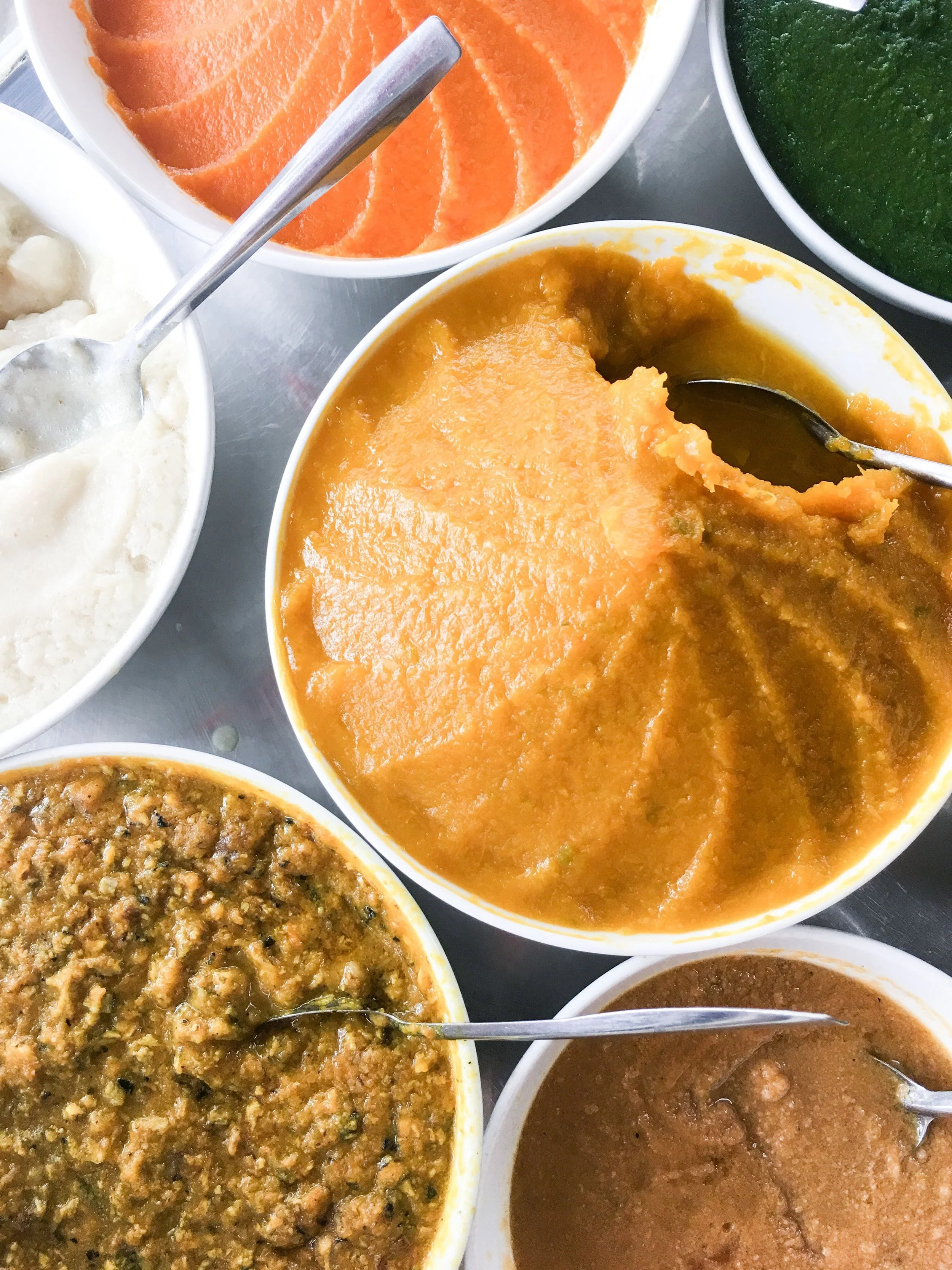 Différents types de purées dans des bols, y compris une orange, une jaune, une verte et une brune. Exemple des repas en texture mixée adaptés à l'alimentation après chirurgie bariatrique.