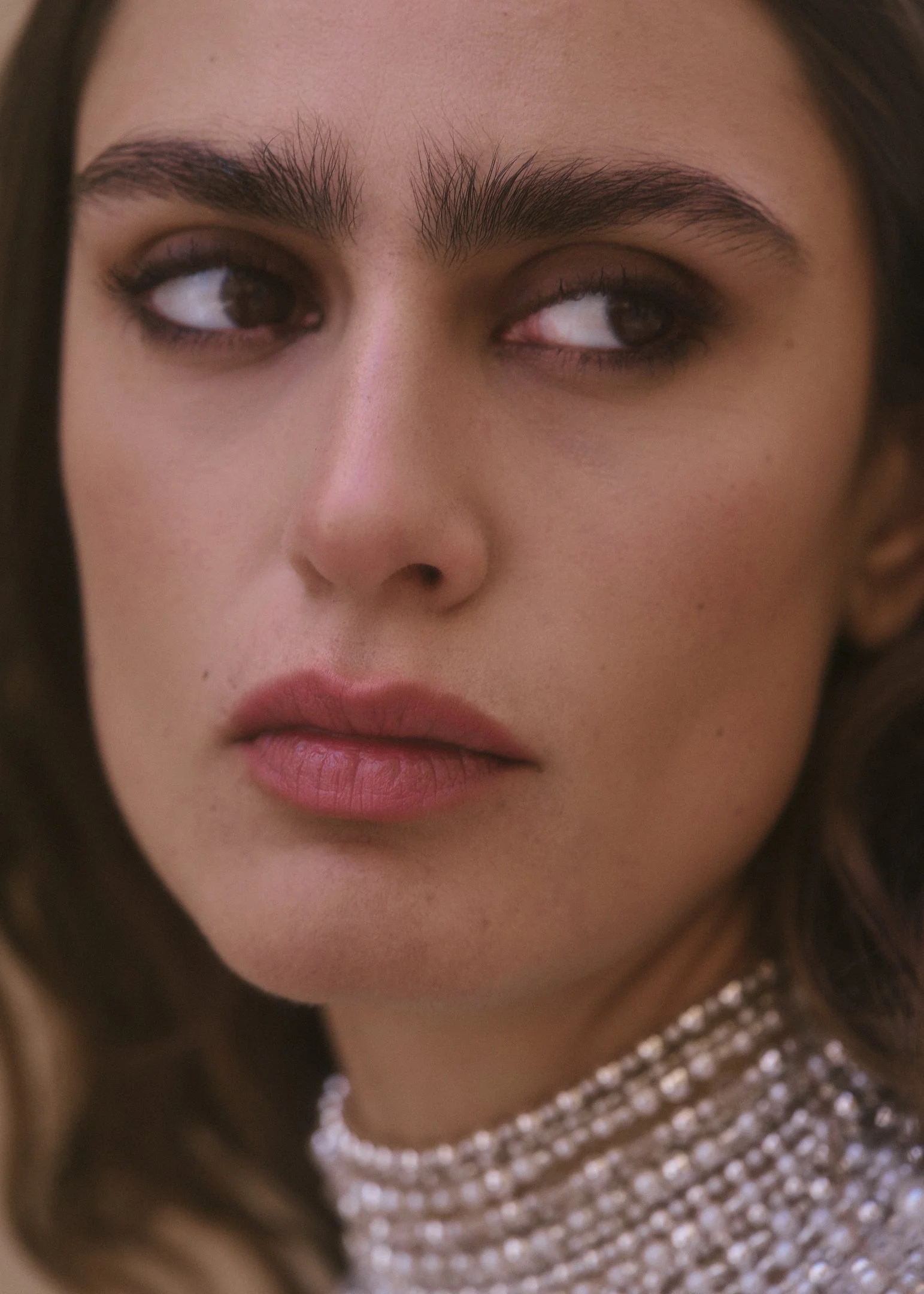 Close-up bridal portrait of Elena with a pearl high-neck collar in warm Spanish light.