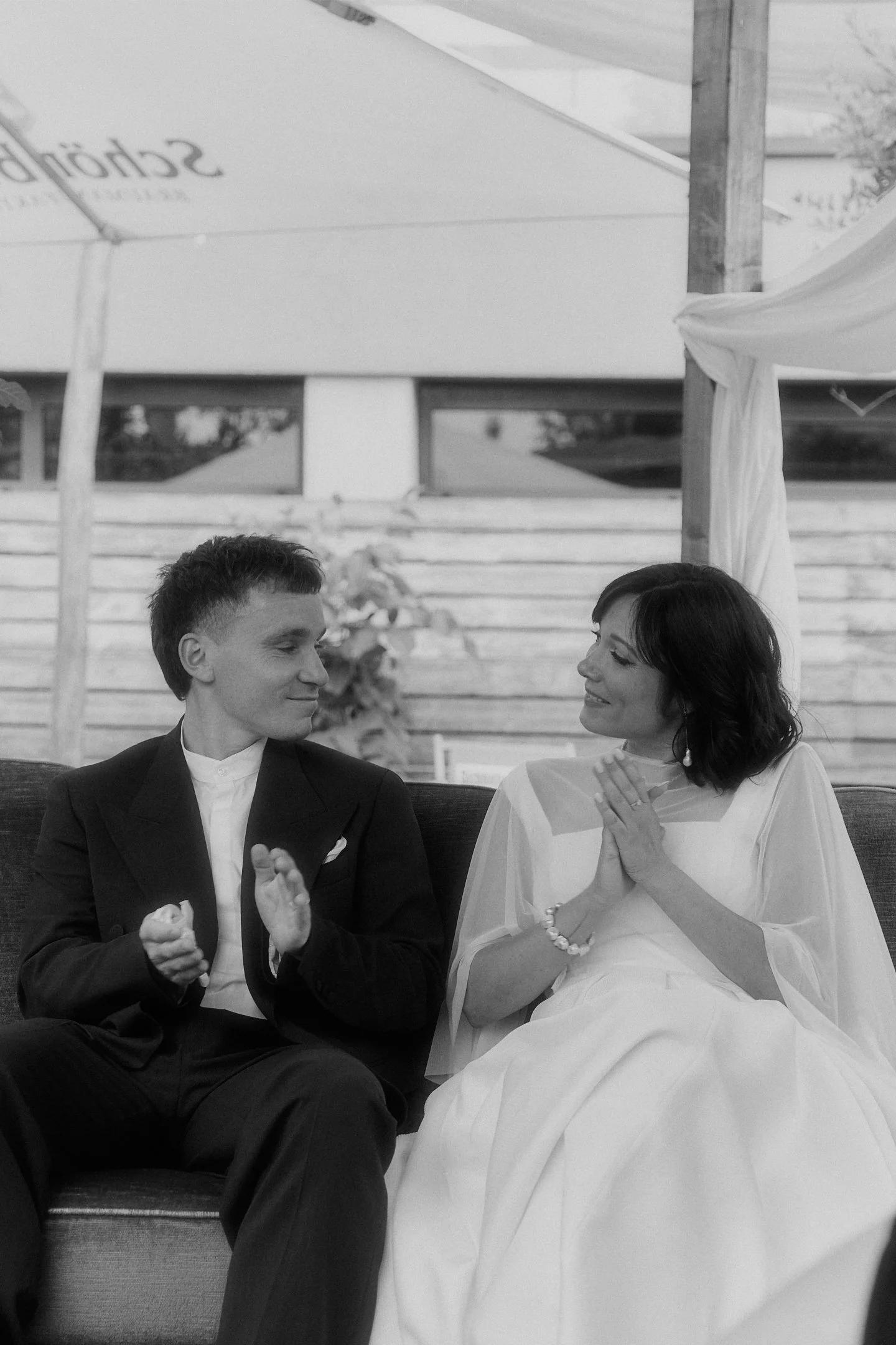 Brautpaar lacht miteinander auf einer Bank während seiner Hochzeit im Hallo Emil Stuttgart.