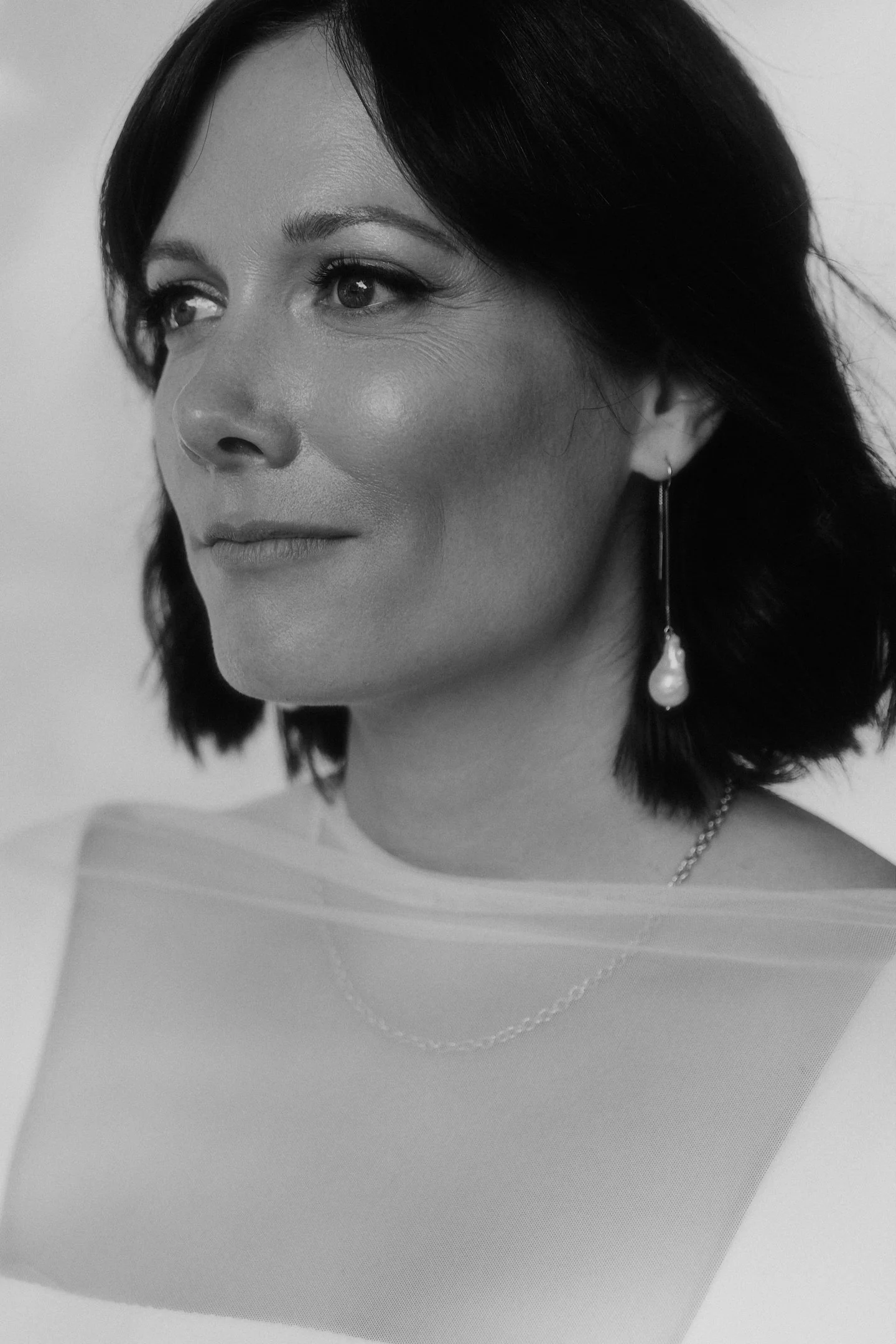 Schwarz-Weiß-Portrait der Braut mit kurzem dunklem Haar und langen Ohrringen bei ihrer Hochzeit im Hallo Emil Stuttgart.
