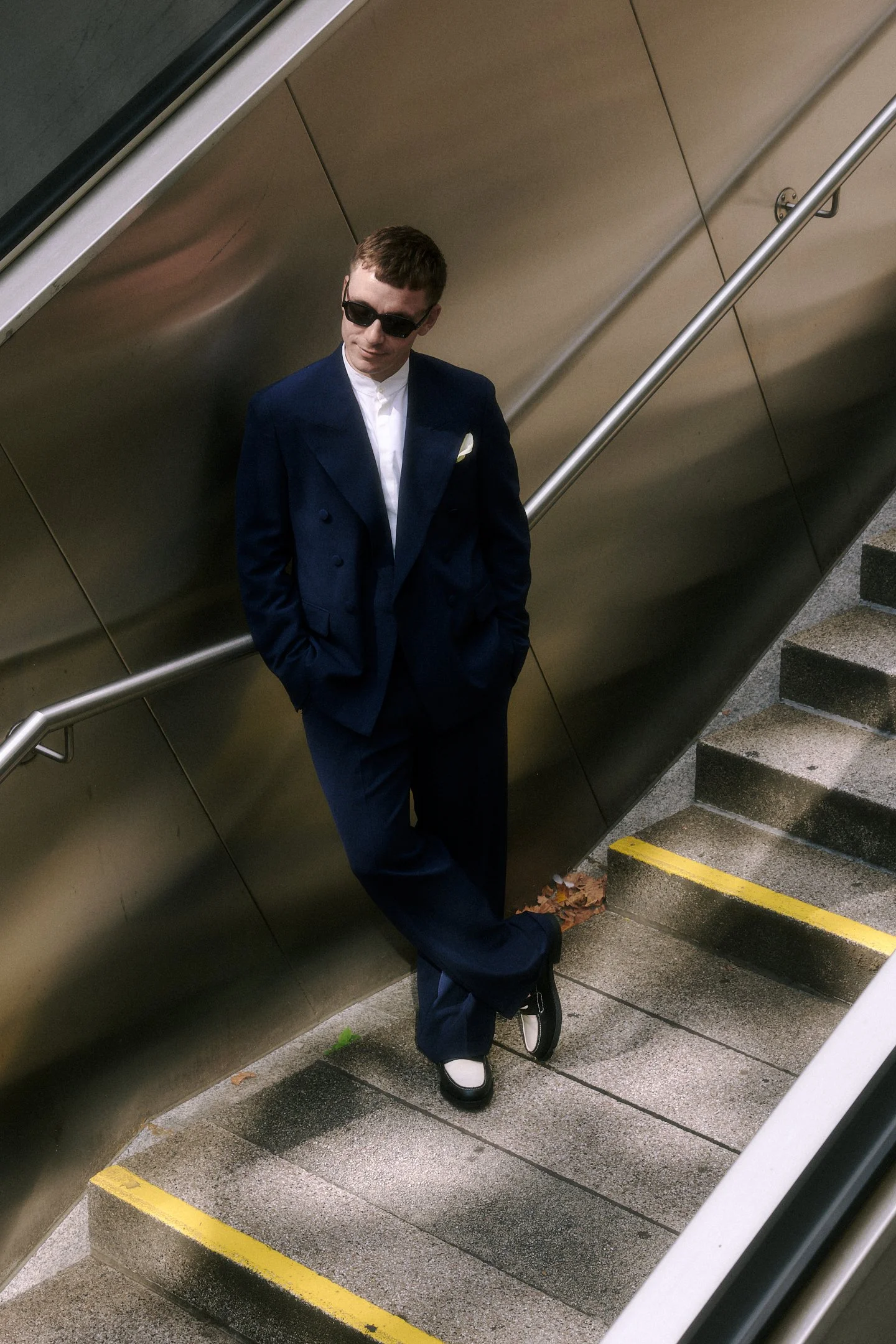 Bräutigam im dunklen Anzug und mit Sonnenbrille bei einer standesamtlichen Hochzeit in Stuttgart, fotografiert auf einer modernen Treppe.