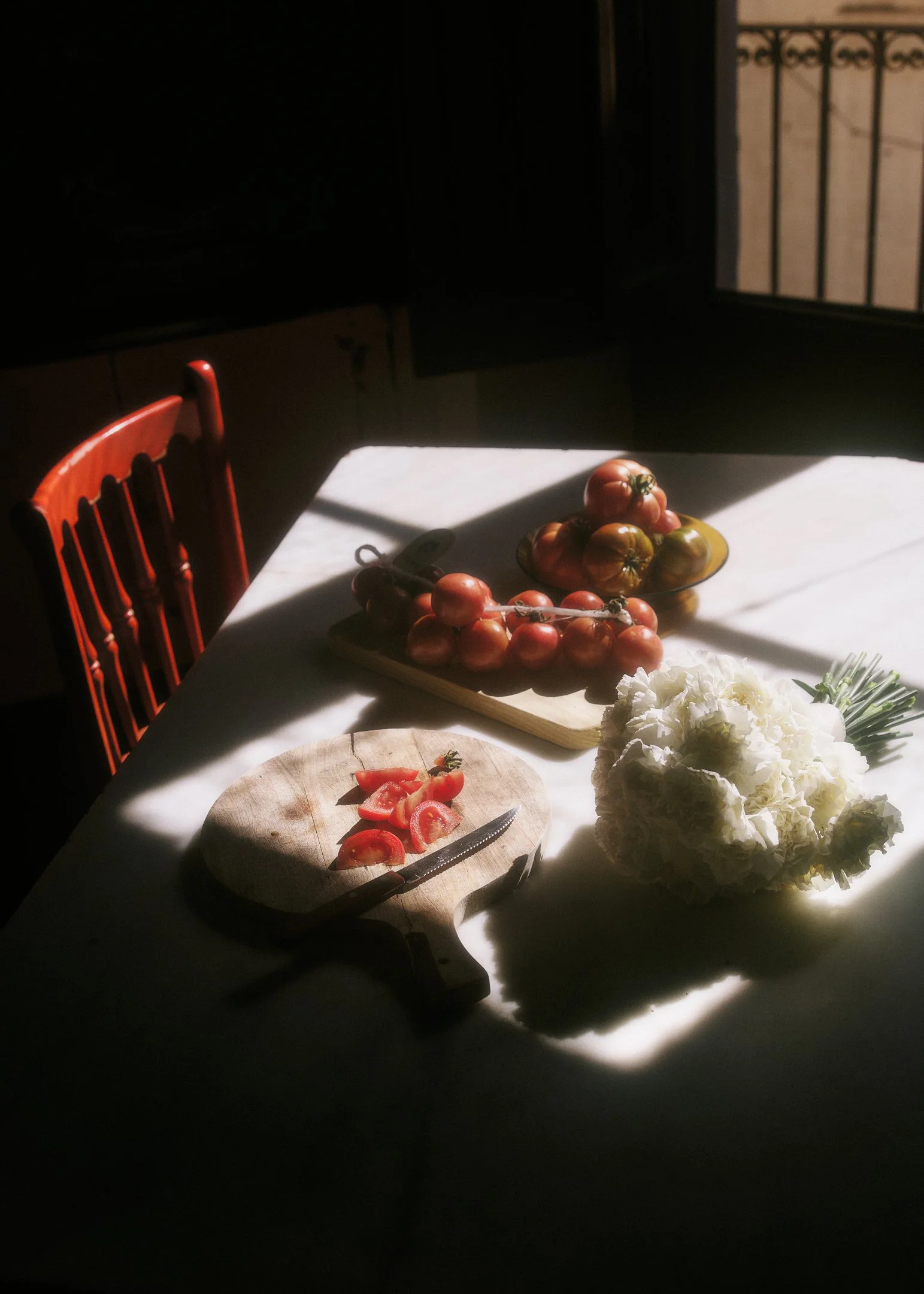 Still life of tomatoes, a cutting board and white hydrangeas in hard Mediterranean light, wedding details in Spain.