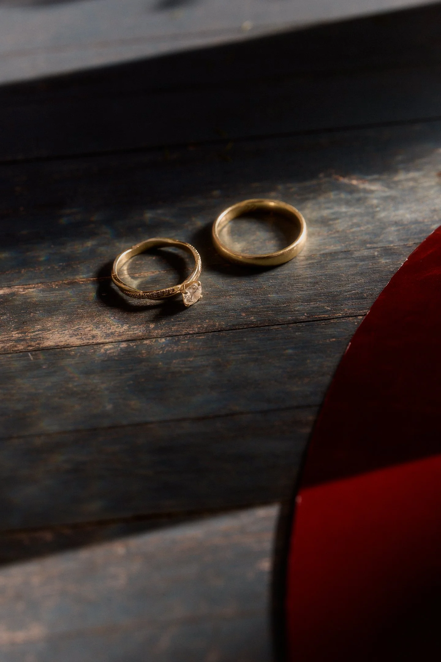 Zwei goldene Eheringe auf einer dunklen Holzfläche neben rotem Stoff – Detail der Hochzeit mit Feier im Hallo Emil Stuttgart.