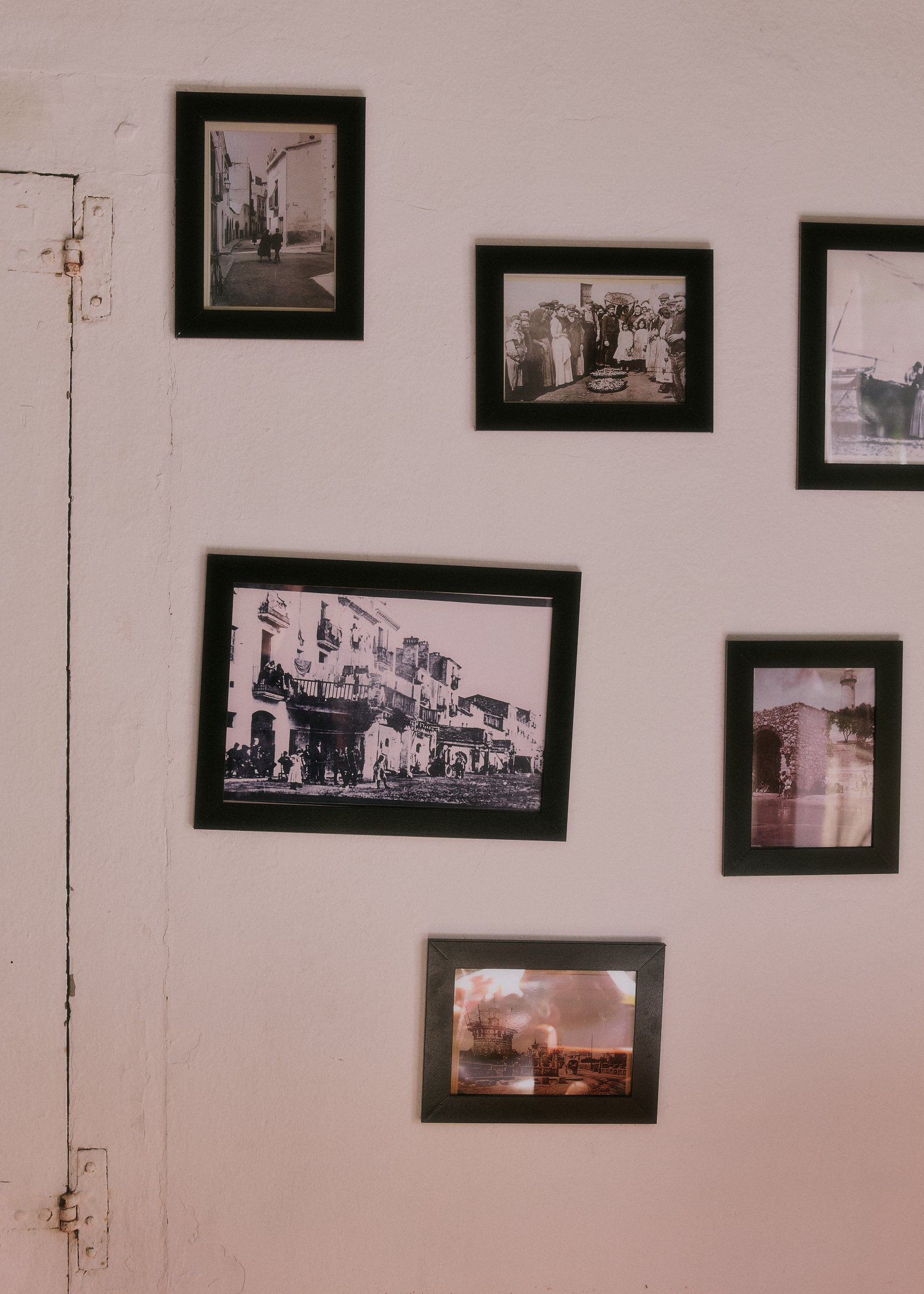Framed black-and-white photographs of the town on a pale pink wall – detail from a destination wedding near Barcelona.