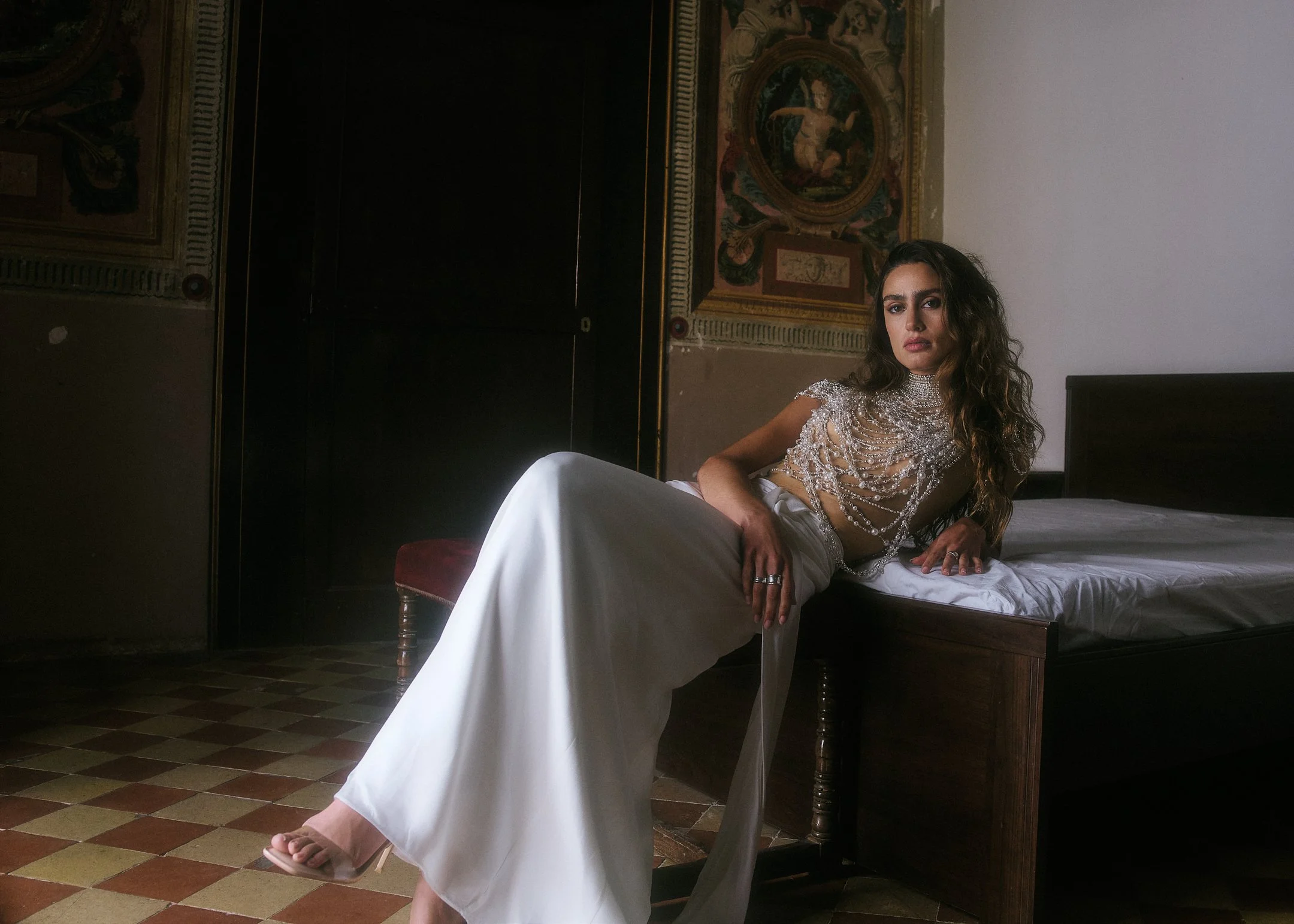 Elena reclining on an antique bed beneath a painted fresco in a historic house near Barcelona.