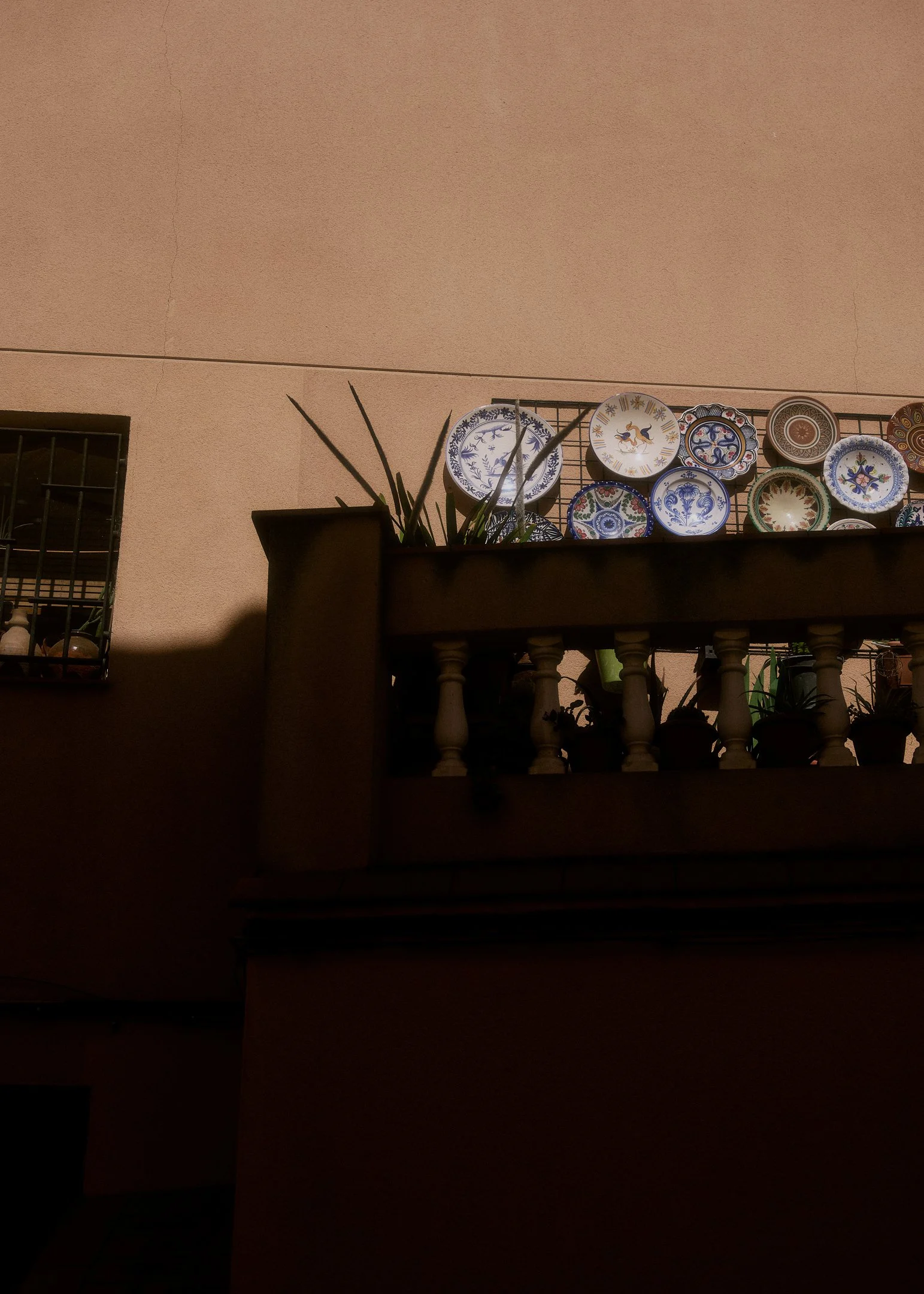 Ceramic plates on a dark wooden dresser in an old Catalan townhouse, interior detail from a wedding near Barcelona.