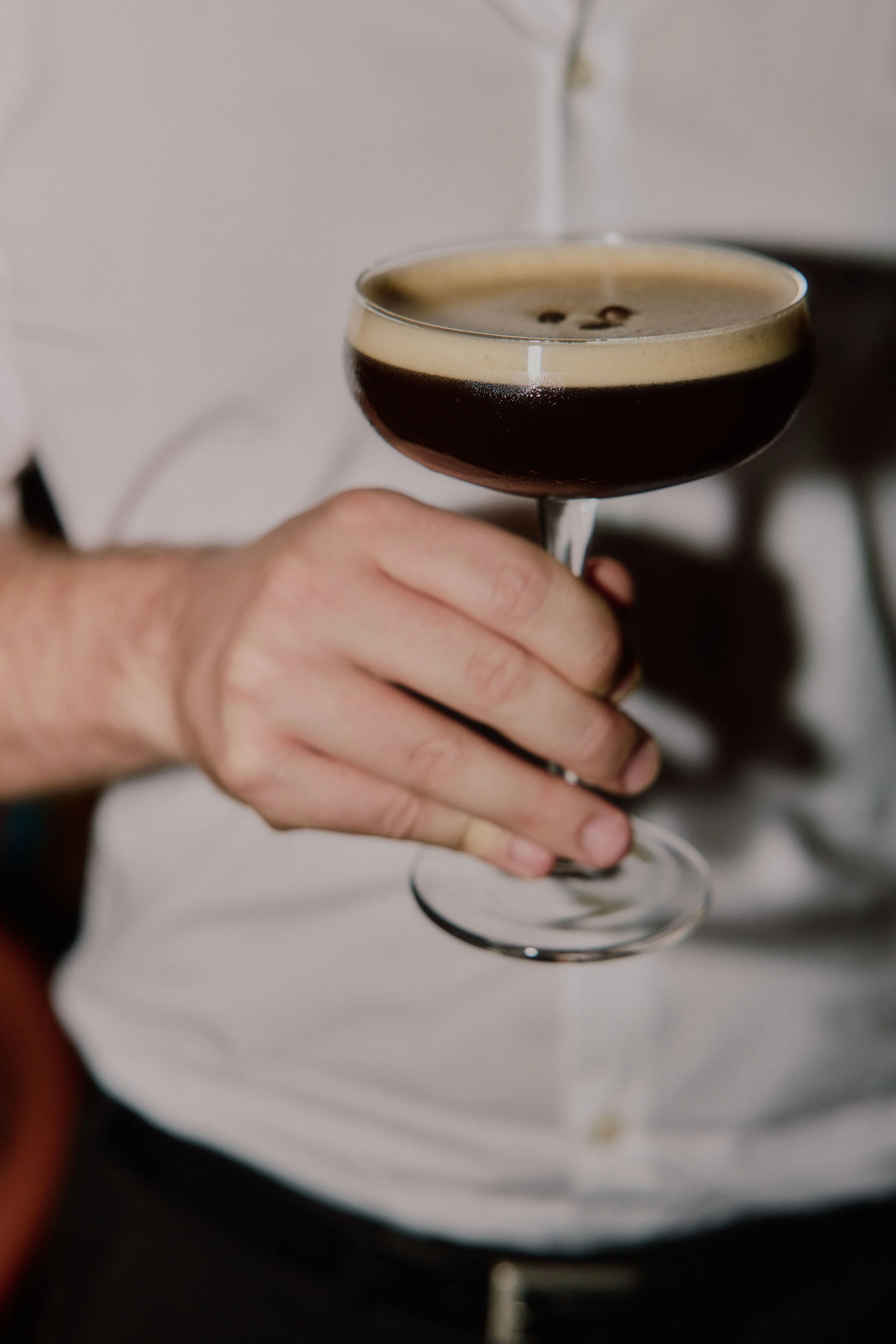 Hochzeitsgast hält einen Espresso Martini mit heller Schaumkrone bei der Feier im Hallo Emil Stuttgart.