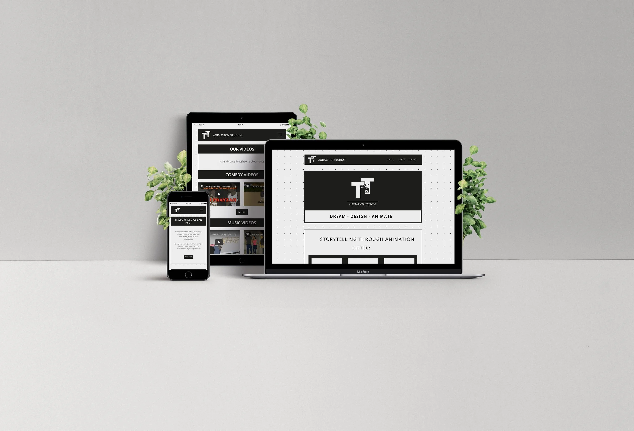 A desktop computer, a tablet, and a smartphone displaying a website for Animation Studios, with greenery in the background against a plain, light gray wall.