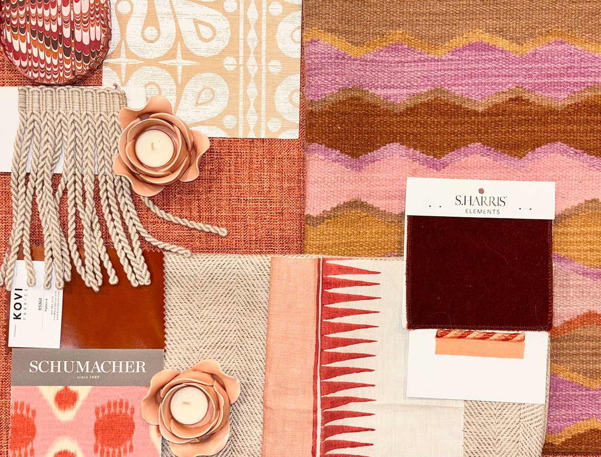 A collection of fabric swatches, a piece of patterned wallpaper, two pink flower-shaped candles, and two different types of decorative textiles, arranged on a flat surface with warm colors like red, pink, and beige.