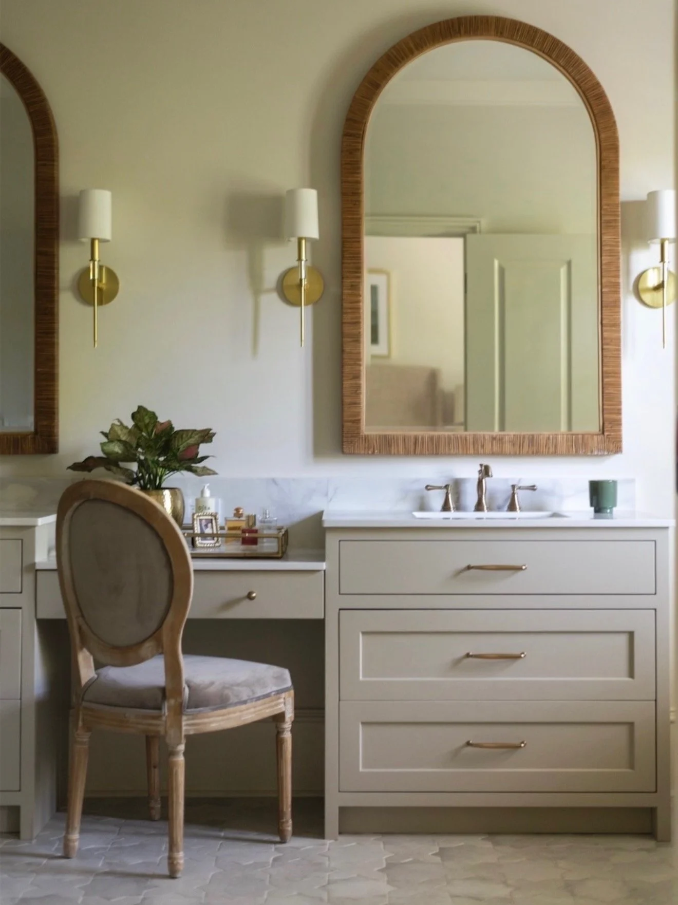 Hill Home Construction, Atlanta, Georgia. A bathroom with a white freestanding baA bathroom vanity area with a large arched mirror with a wooden frame, two wall-mounted sconces with white shades, a white dresser with a tray holding perfume bottles,.