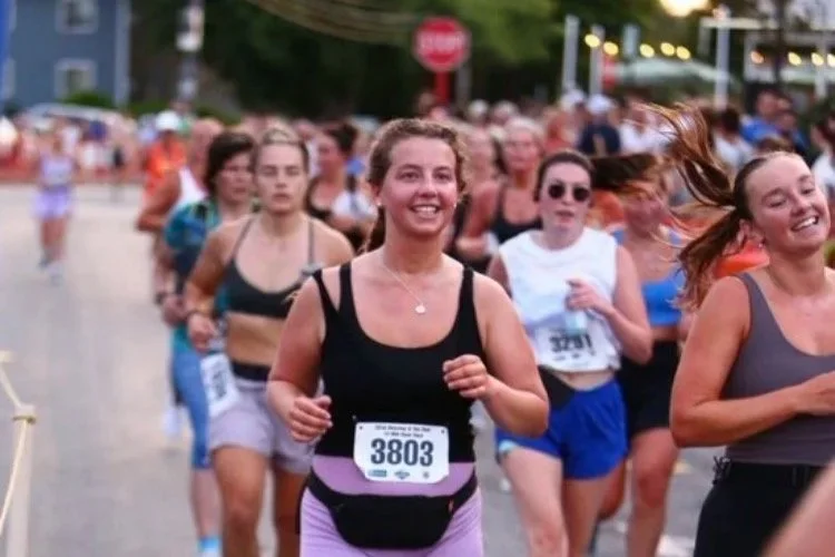 Group of people running in a race outdoors, with Emma smiling in the foreground