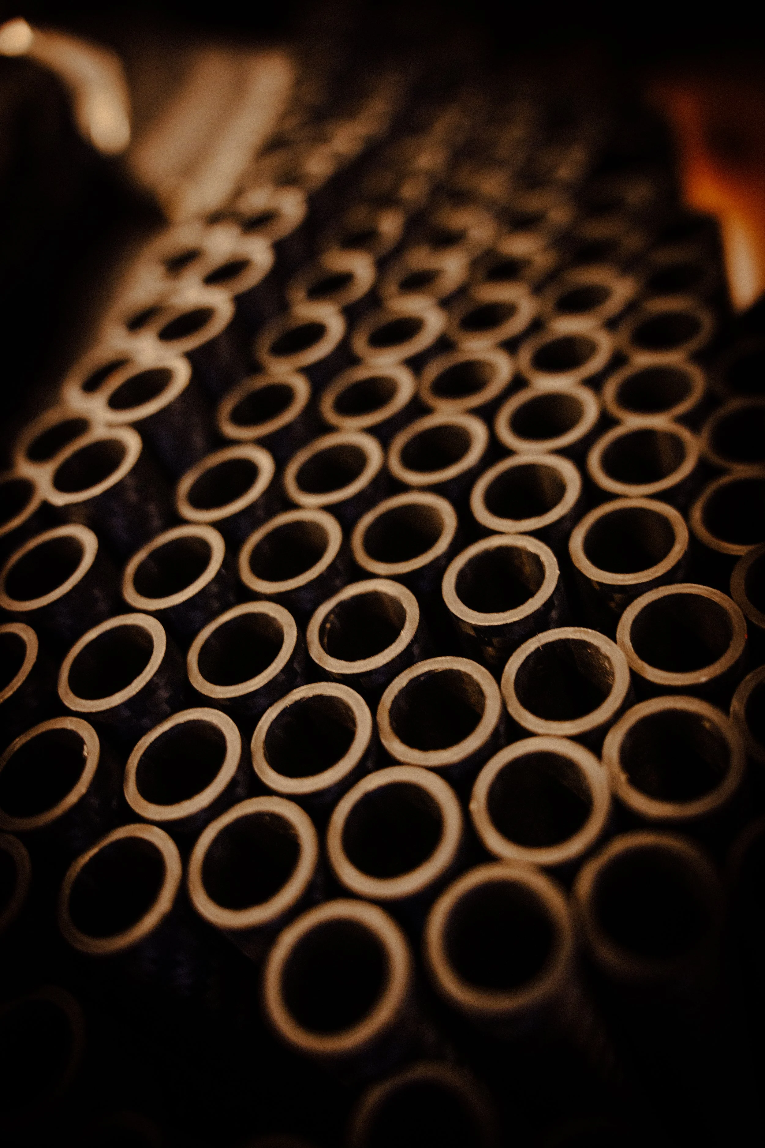 Close-up view of stacked, hollow, cylindrical pipes or tubes, arranged in a pattern.
