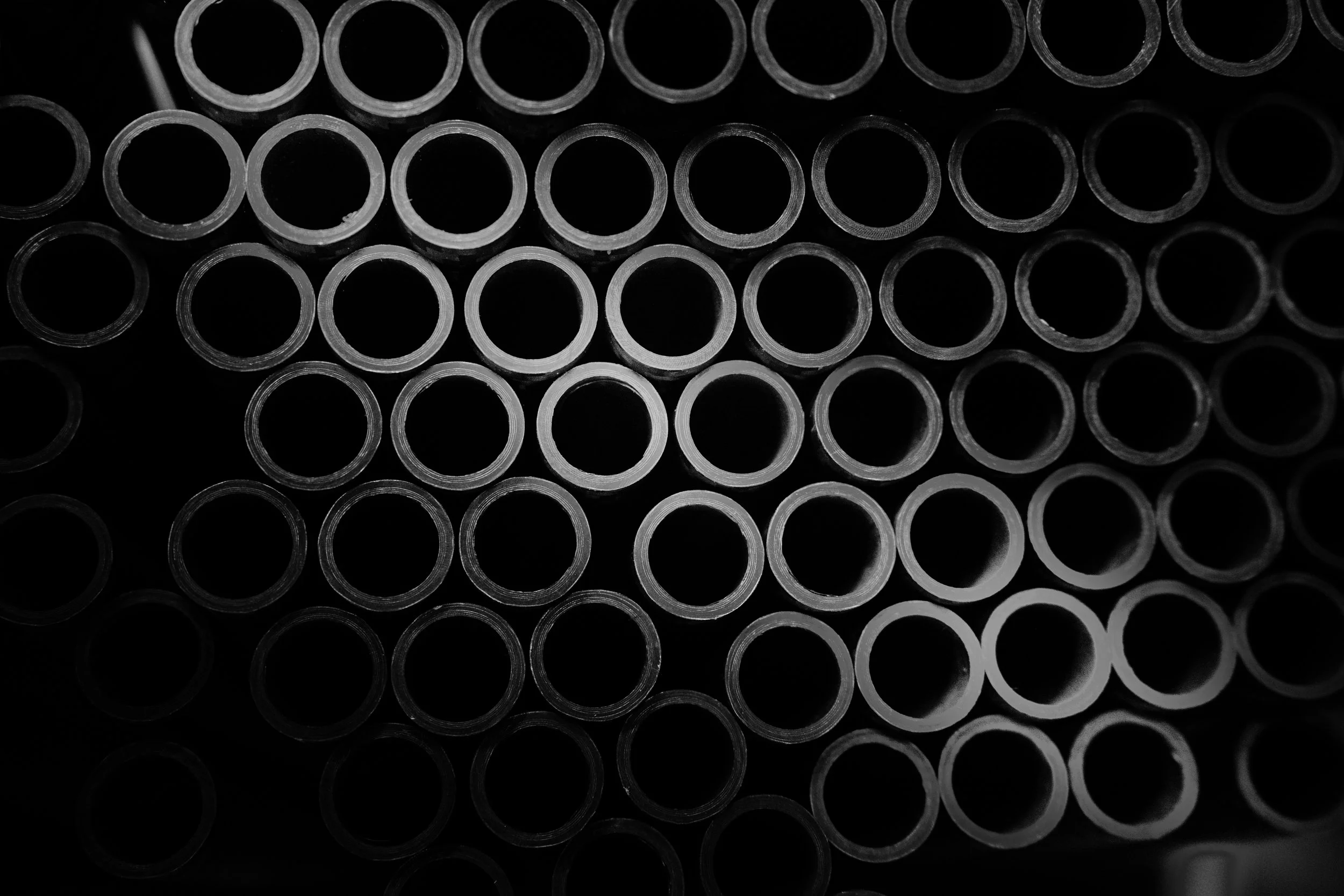 Close-up of a stack of black metal pipes arranged in parallel rows.