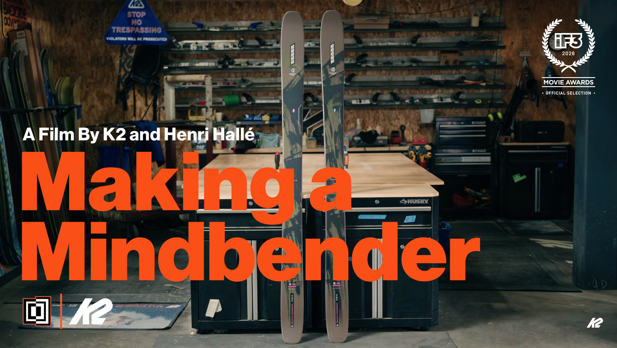 Two skis standing upright on a workbench in a workshop surrounded by tools and equipment.