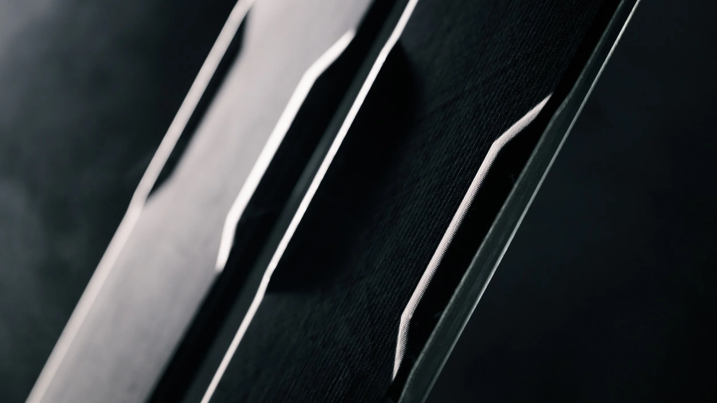 Close-up of a sleek black speaker with a silver trim and textured grille.