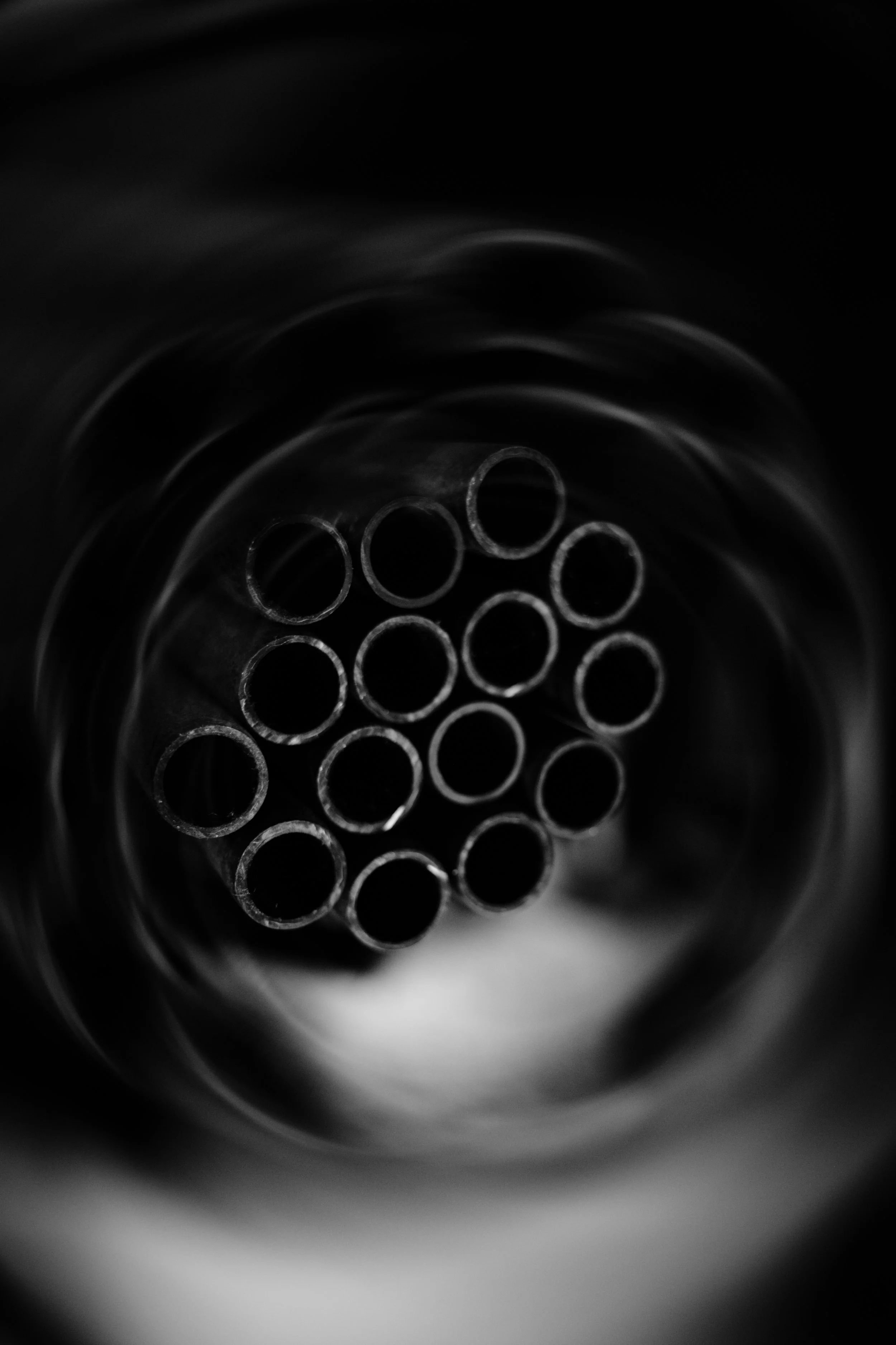 Close-up of the circular openings of a metal pipe with a dark background.