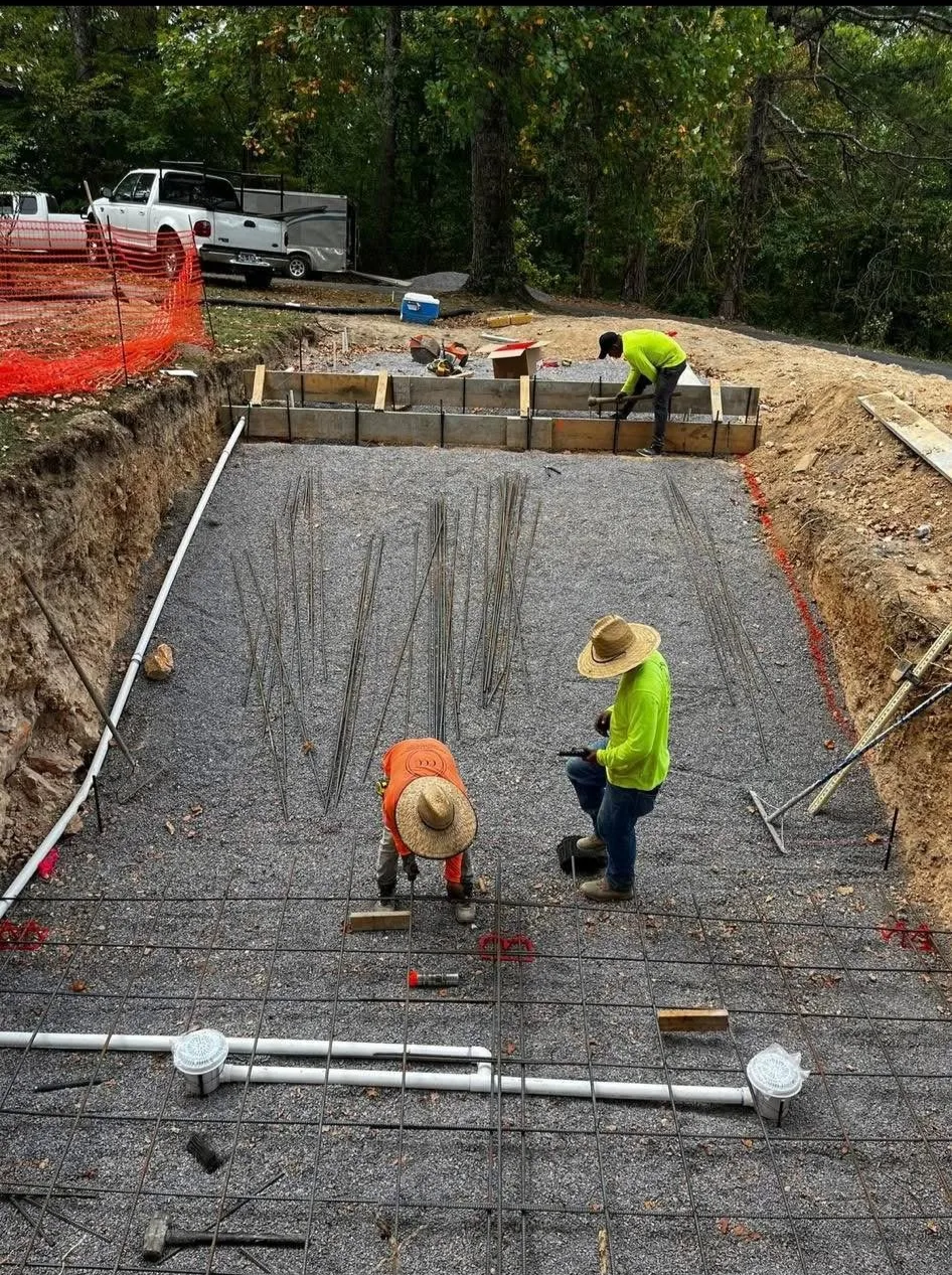 two concrete workers laying rebar to prep a project