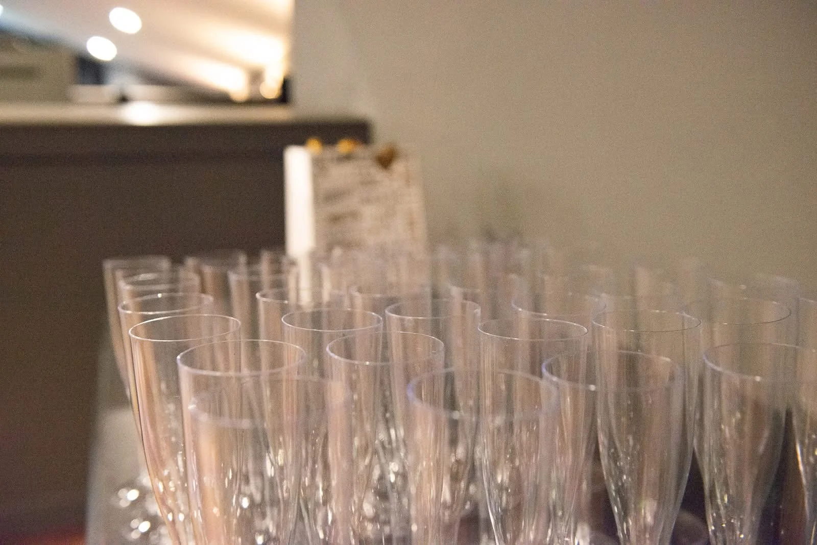 Multiple empty champagne flutes arranged in rows on a table with a blurred background.