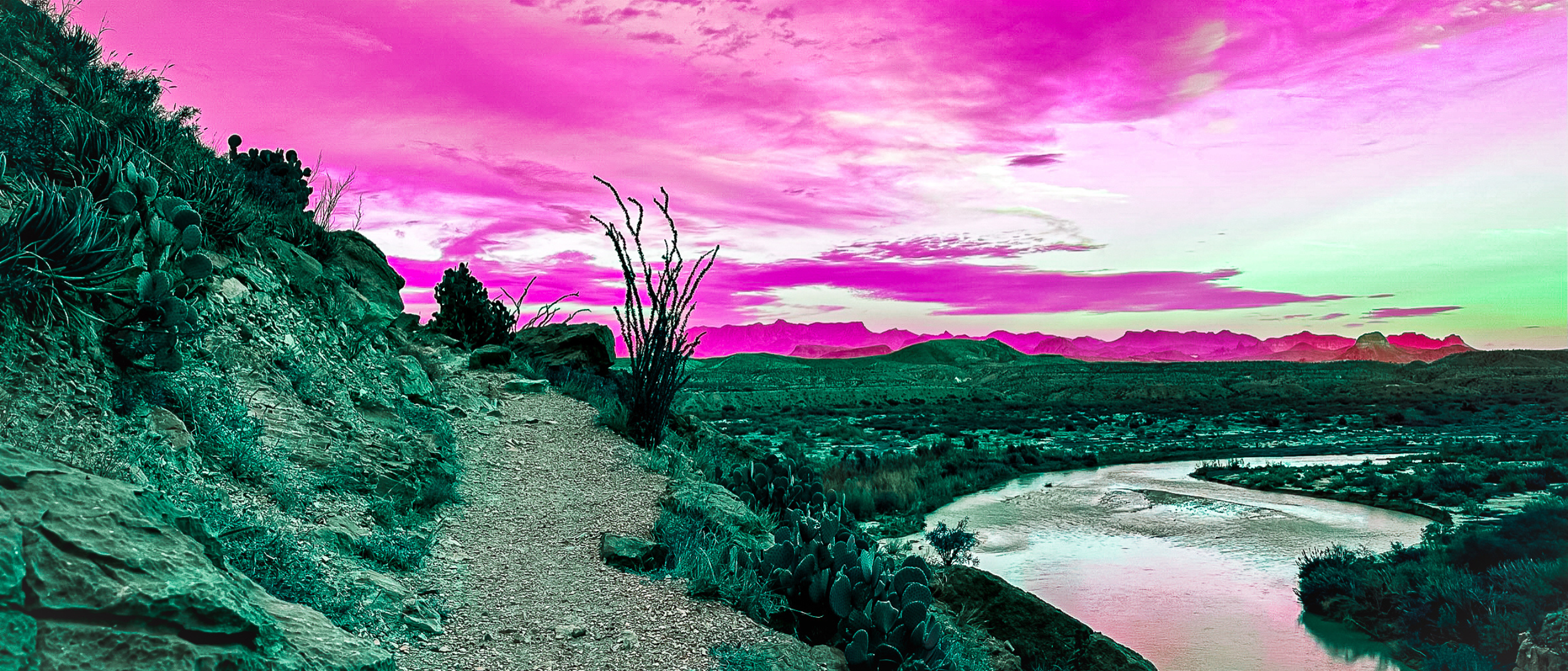 A desert landscape with a trail on a rocky hillside, desert plants, and a river in the background. The sky is a gradient of pink, purple, and green hues.