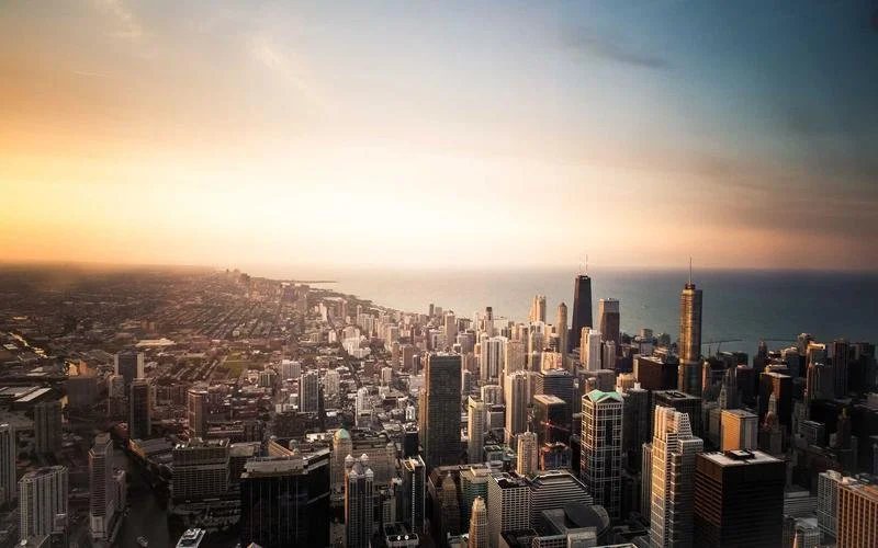 Aerial view of Chicago skyline at sunset with Lake Michigan in the background.