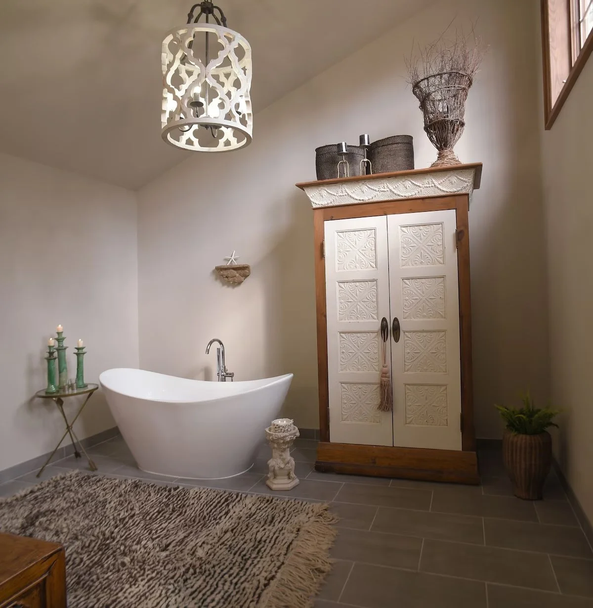Bathroom with clawfoot tub, rustic cabinet, decorative items, and a chandelier.