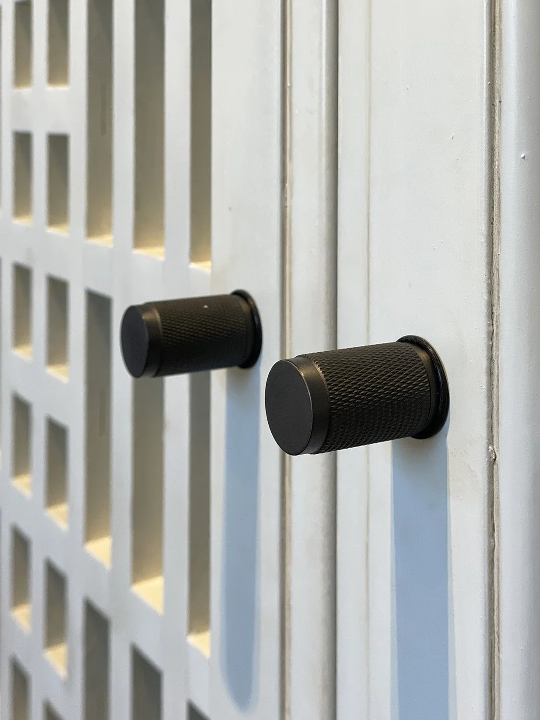 Dettaglio di maniglie in metallo su porte di legno bianco.