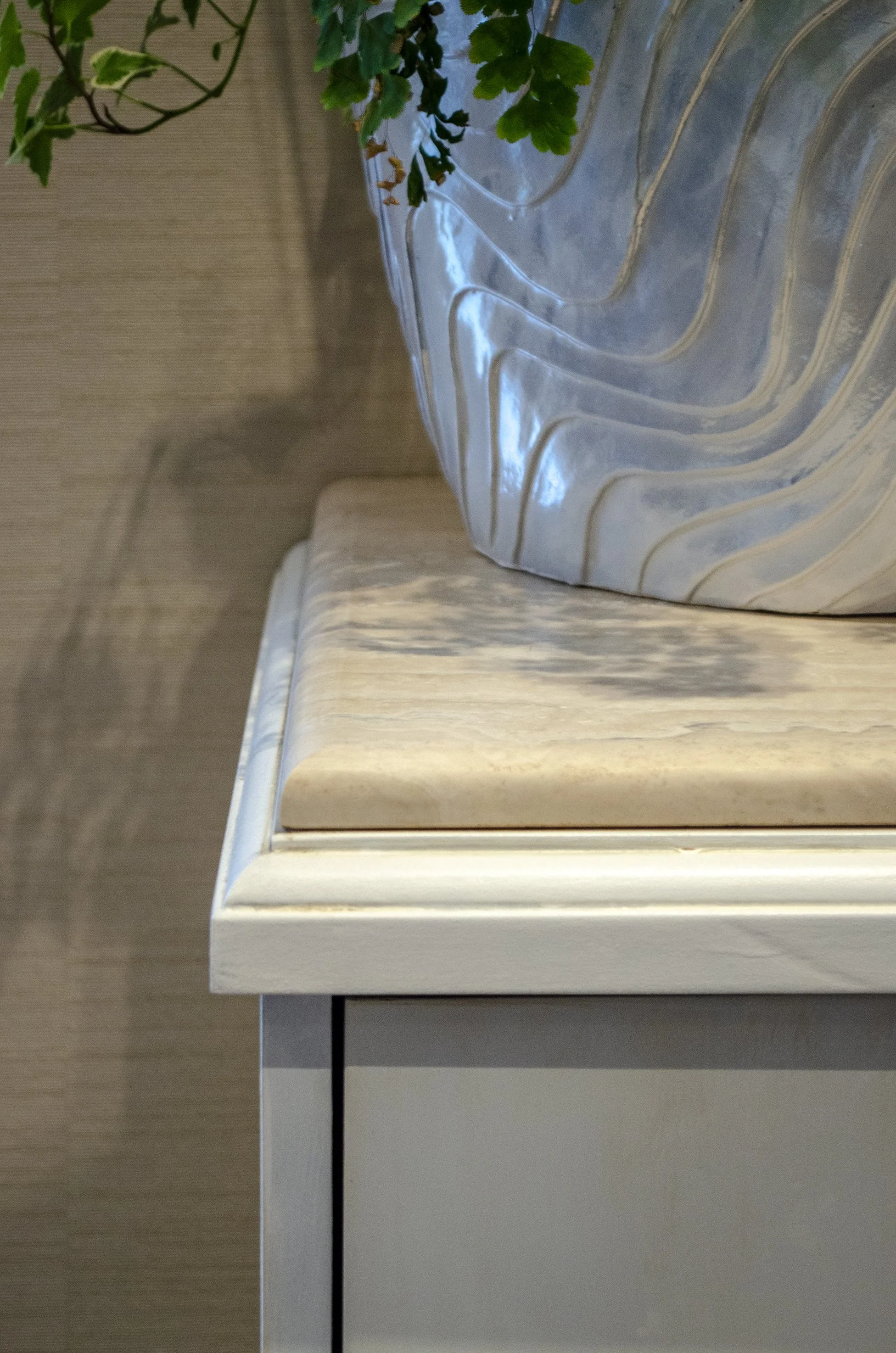 Dettaglio di un mobile in legno bianco e piano di marmo chiaro.