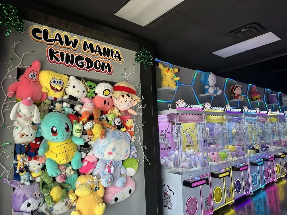 A colorful arcade with claw machines filled with plush toys on the right and a stuffed toy display titled 'Claw Mania Kingdom' featuring characters like Patrick, SpongeBob SquarePants, Hello Kitty, and Pikachu on the left.