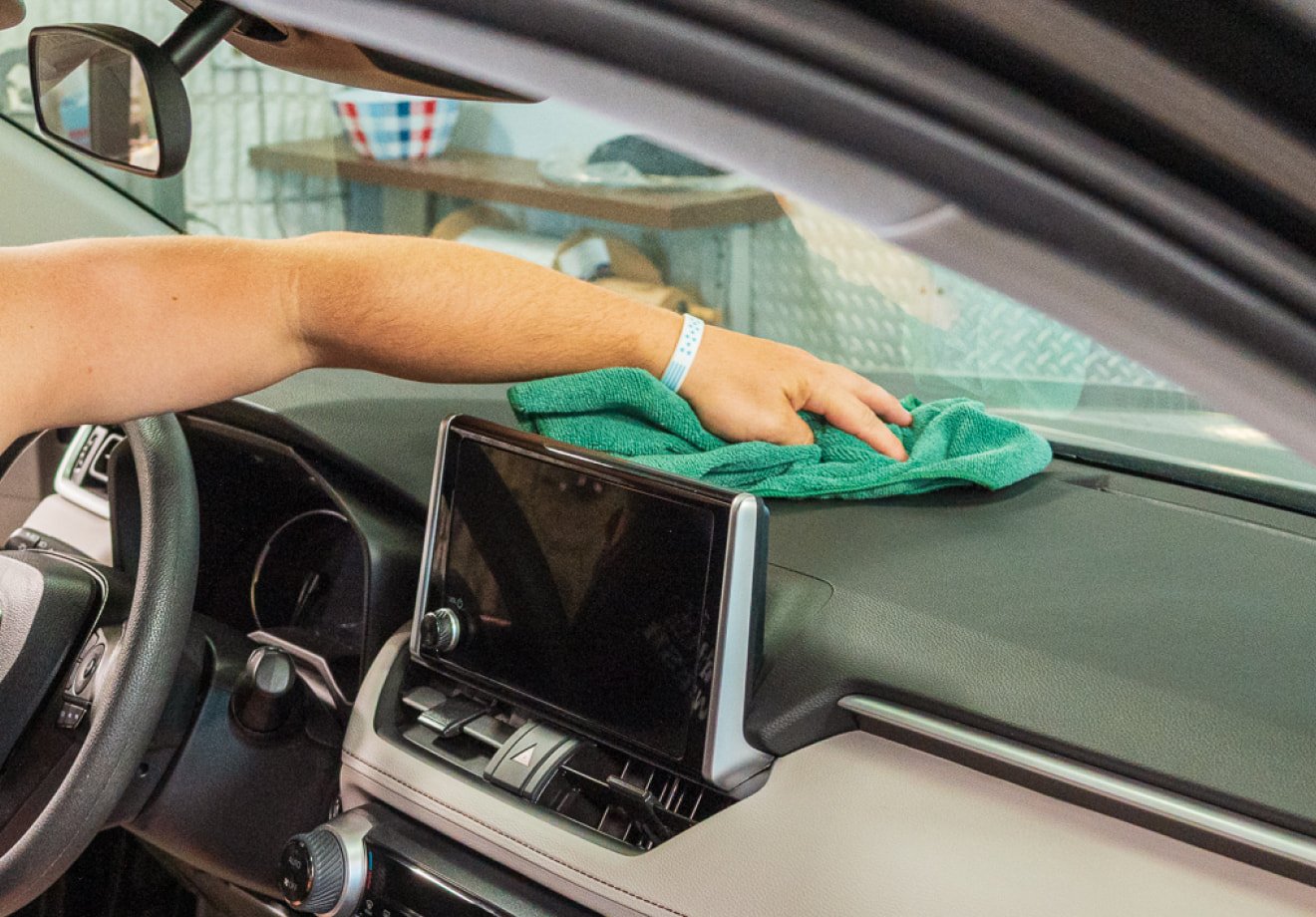 Employee cleaning a vehicle dashboard during an interior detail at The Franklin Car Wash