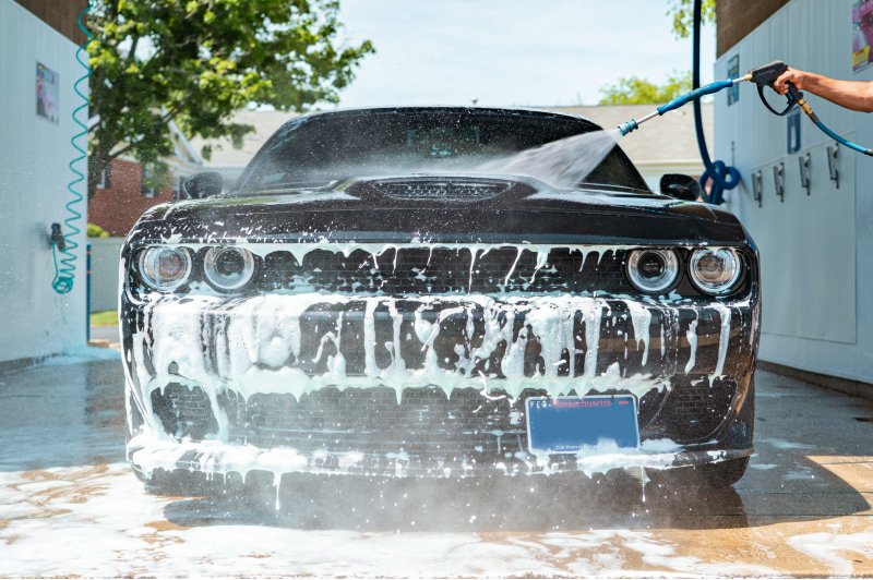 Customer pressure washing a vehicle at a Franklin Car Wash self-service bay